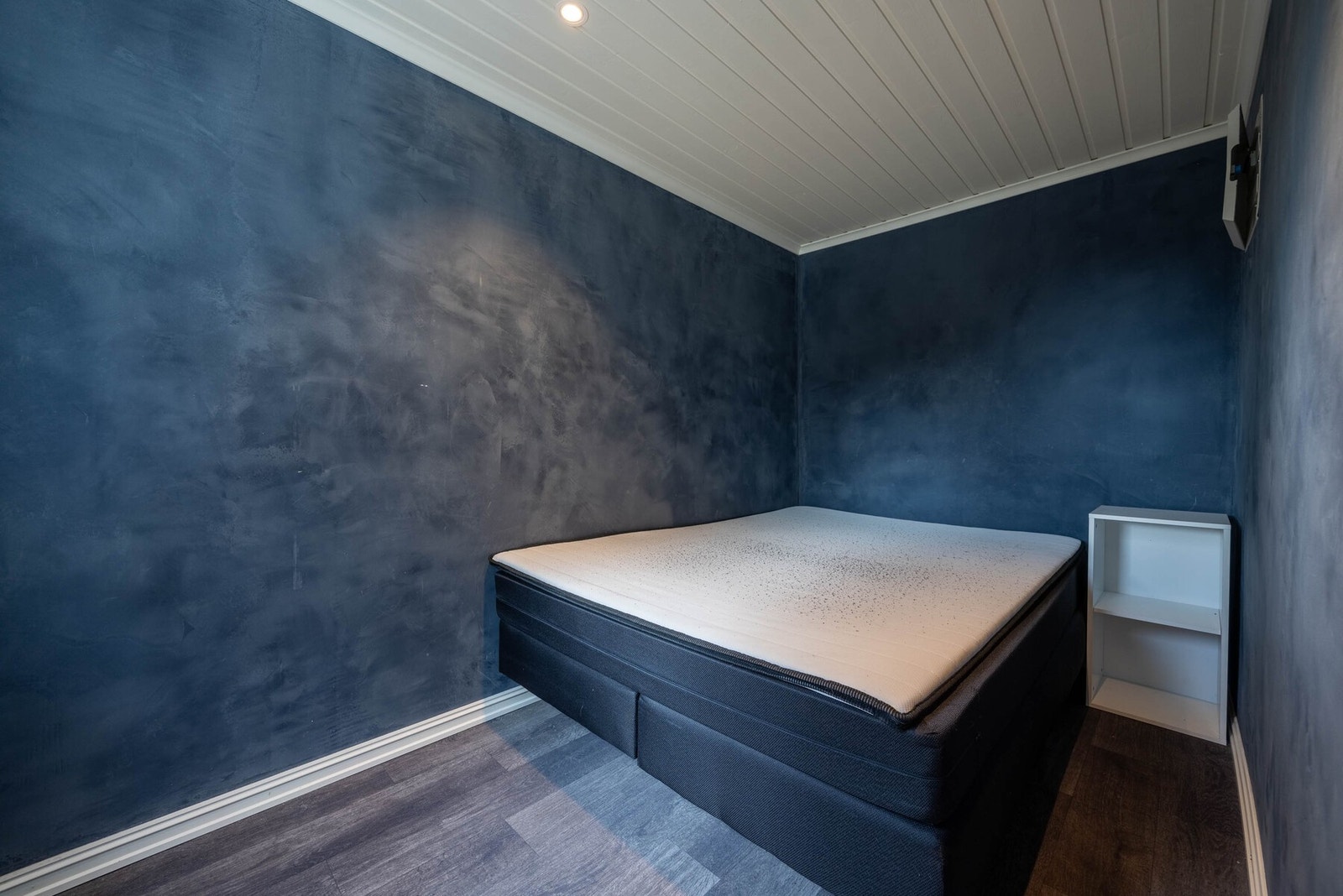 Soverom i sokkelleiligheten med mørke vegger som skaper en lun atmosfære. Galleribilde