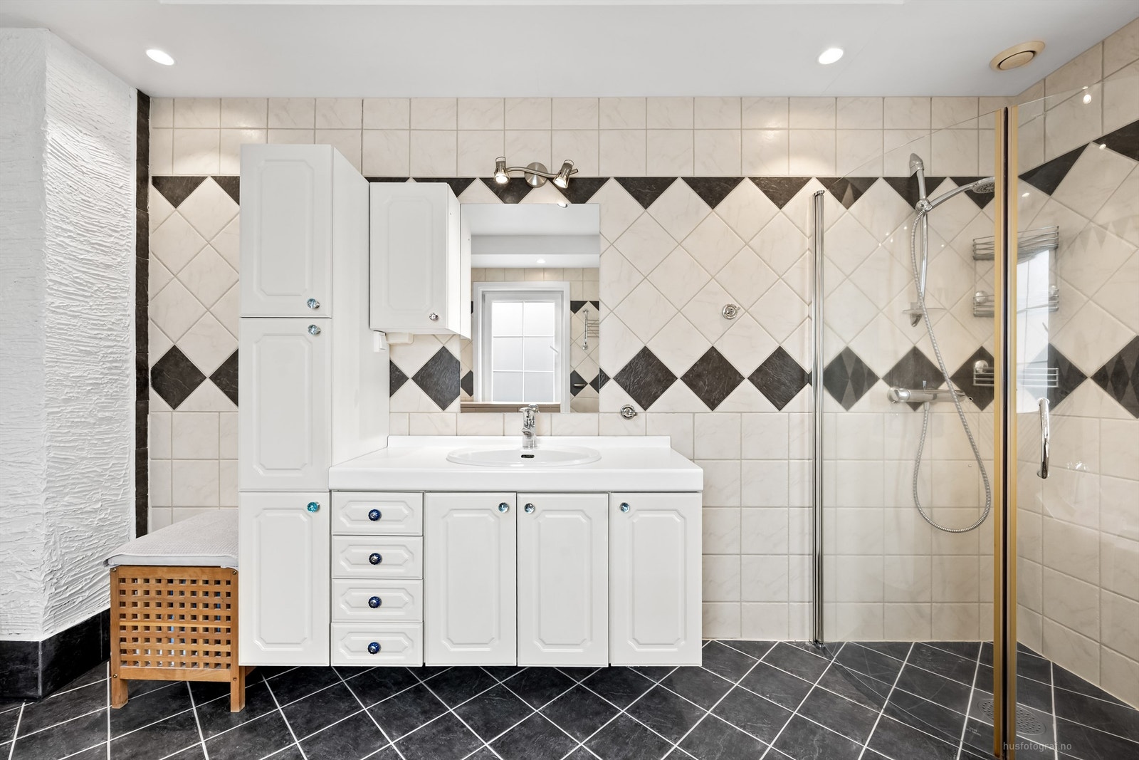 Badet har dusjhjørne med foldedører av glass og innfliset hjørnebadekar med hånddusj Galleribilde