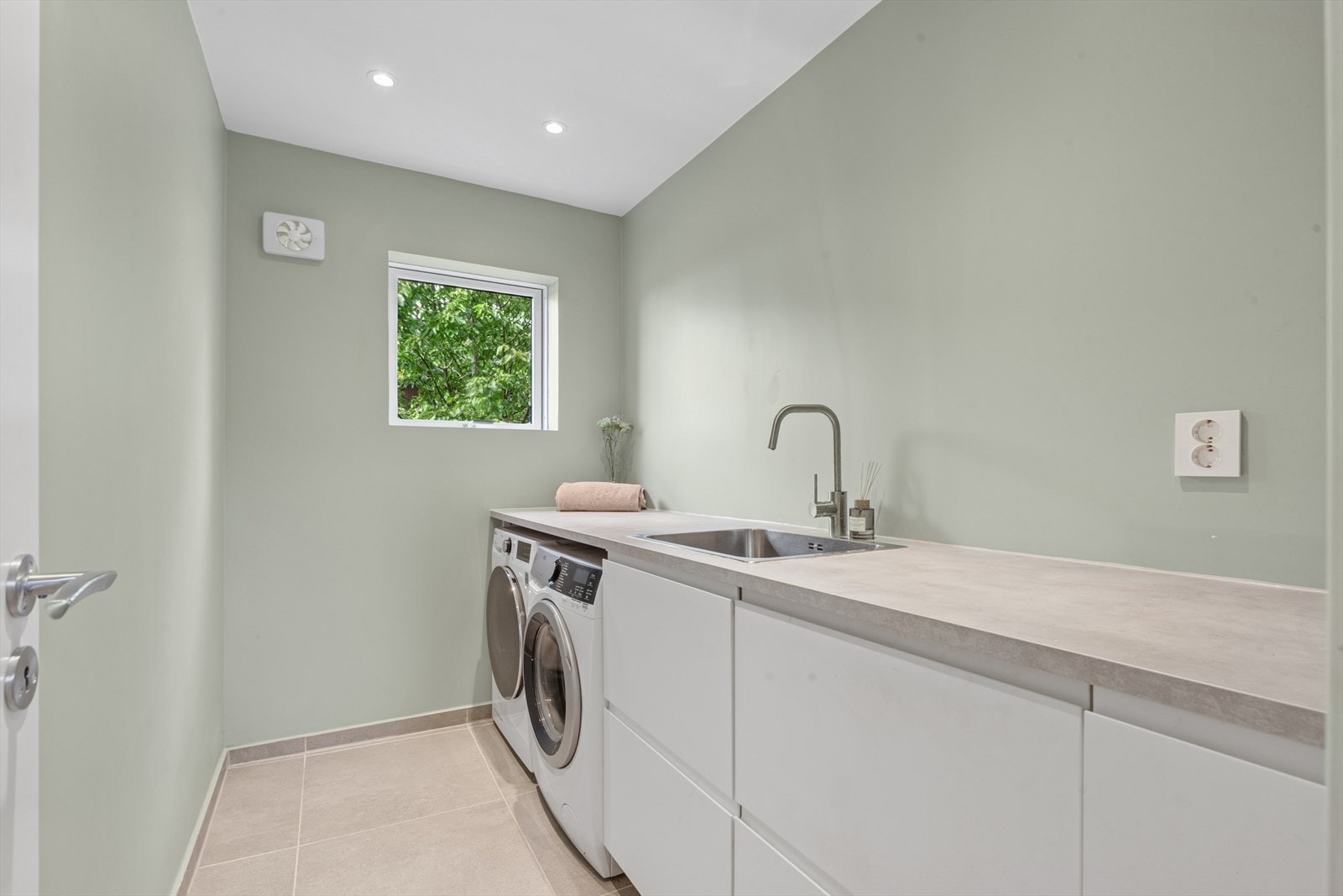 Vaskerom fra 2021. Malte flater på vegg og fliser på gulv. Gulvvarme. Rommet har benkeinnredning, utslagsvask med ett-greps bl. batteri, gulvsluk og opplegg for vaskemaskin. Avsatt plass til tørketrommel. Innredning fra 2019. Elektronisk styrt vifte. Galleribilde