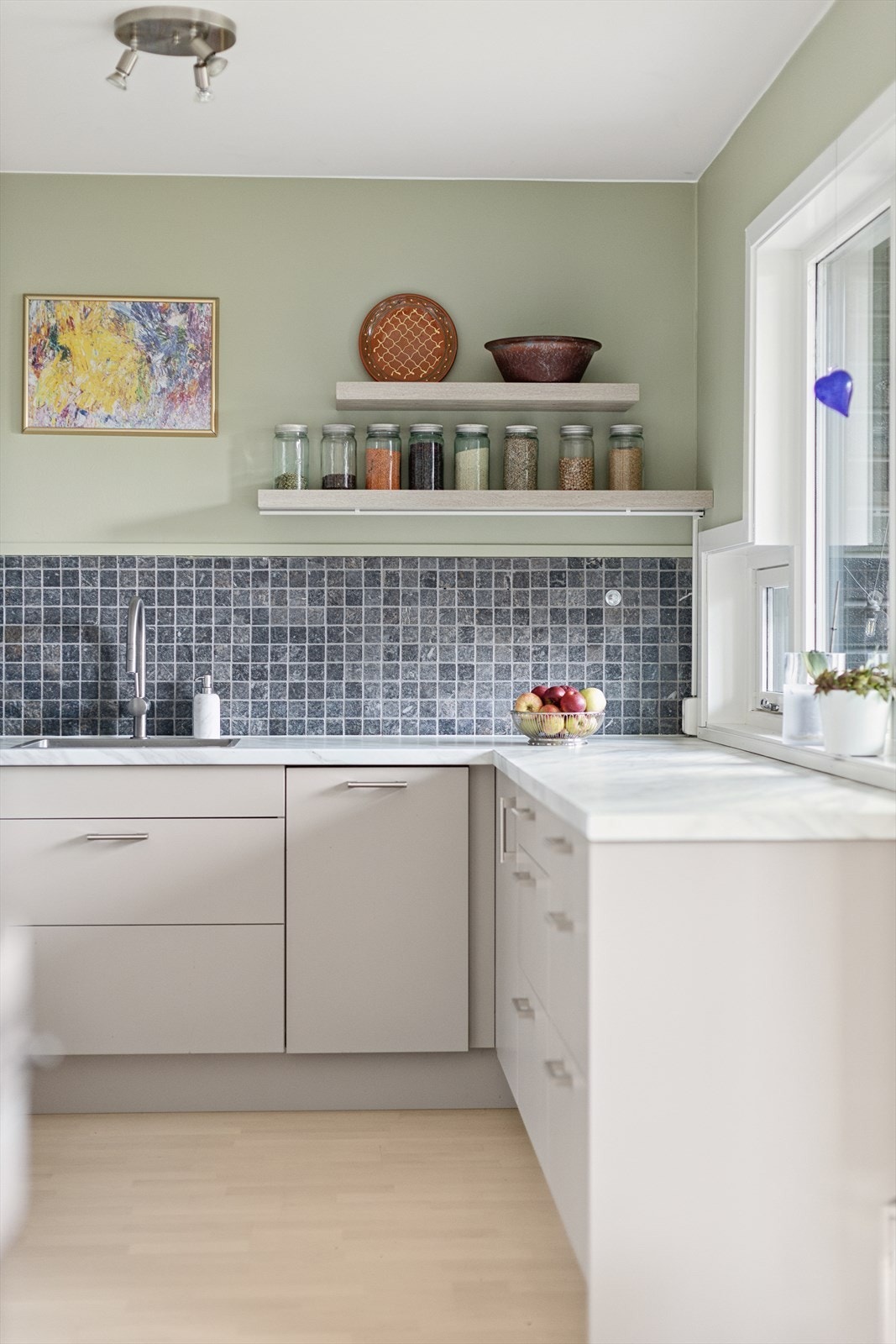 Over benken er det stilige mosaikkfliser, stikkontakter og god belysning med lys under overskapene. Galleribilde