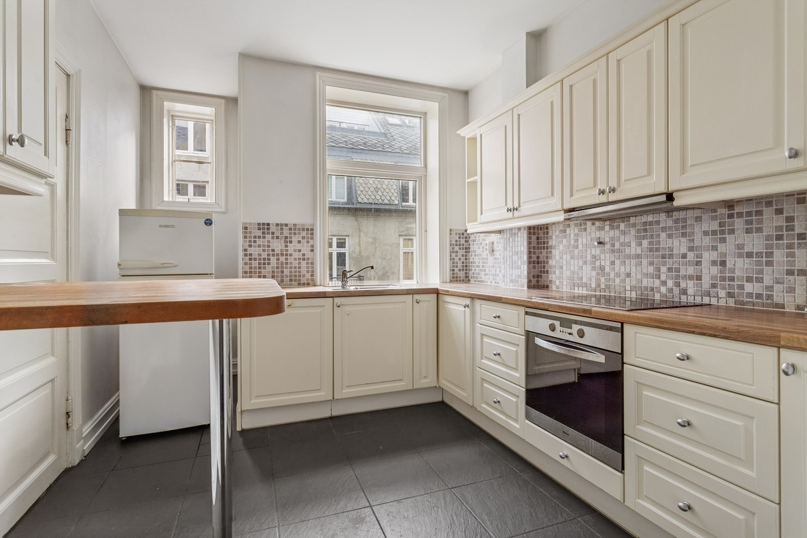 Nisje med plass for kjøleskap. Praktisk halvøy perfekt som frokostbord. Dør til baktrapp nås via kjøkkenet. Galleribilde