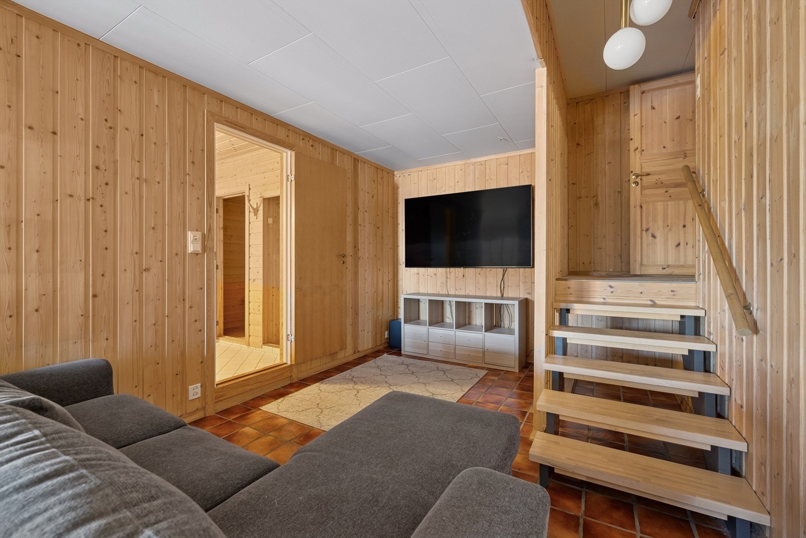 Stor og luftig stue som er gjennomført med lys panel på veggene og flislagt gulv. Galleribilde