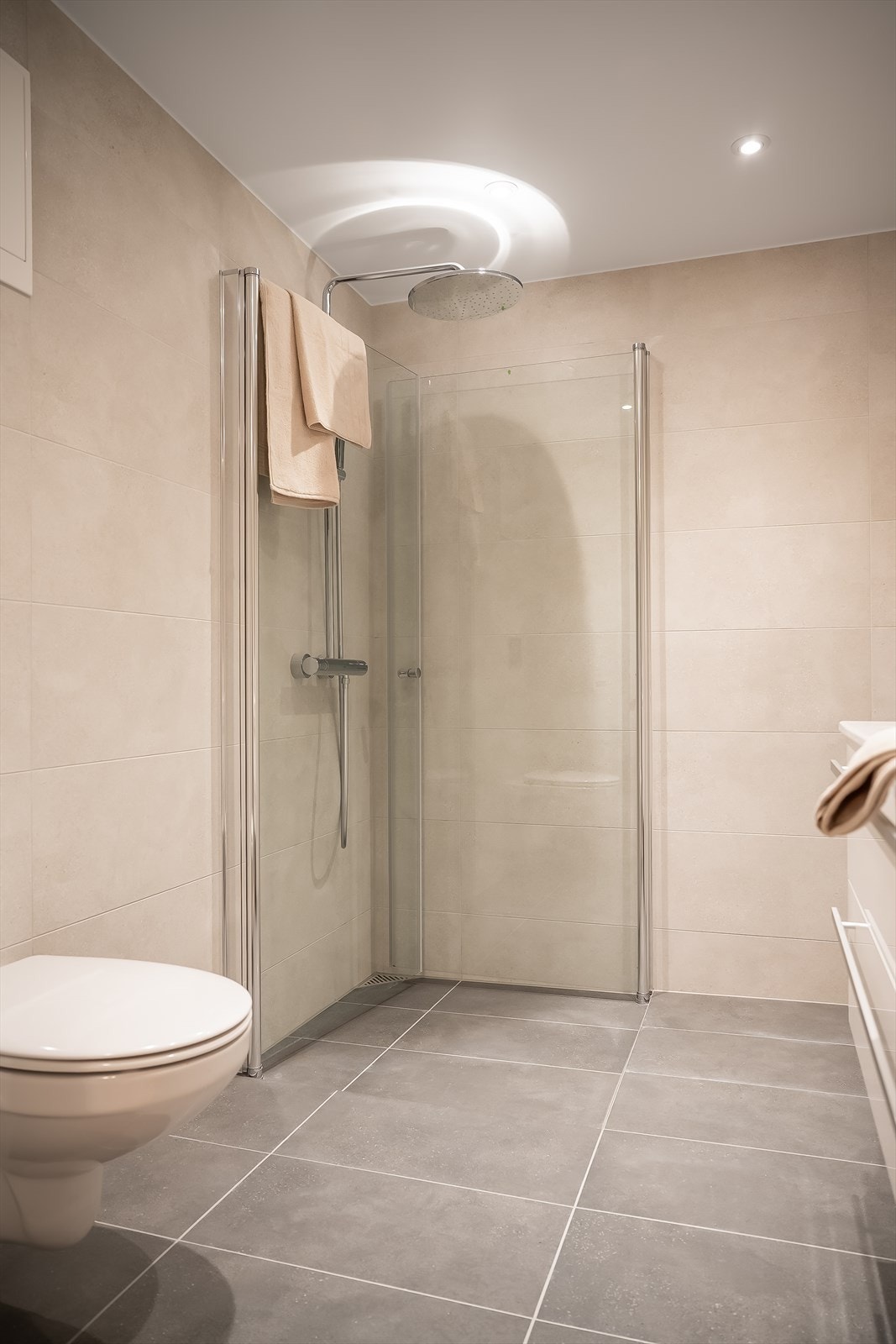 Innenfor walk-in garderoben får du et lekkert bad med innsvingbare dusjdører og regndusj fra Grohe. Galleribilde