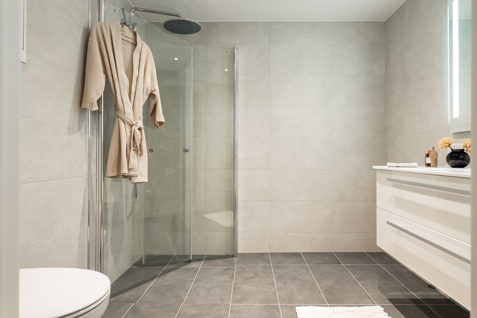 Leiligheten har 2 baderom. Ved soverom 2 finner du et lekkert baderom med innsvingbare dusjdører og regndusj fra Grohe. Galleribilde