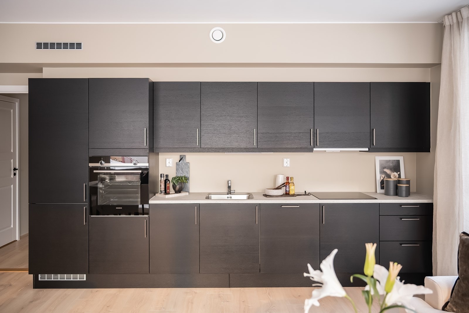 Kjøkkenet er levert av det danske designmerket HTH. Frontene er oppgradert med den lekre modellen focus sort eik finer og er komplettert med hvitevarer fra kvalitetsleverandøren Siemens. Galleribilde