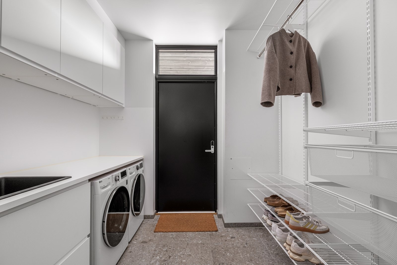 Et praktisk vaskerom med varmekabler i gulvet, utslagsvask og opplegg for vaskemaskin, som gjør daglige gjøremål enkle og komfortable. Galleribilde