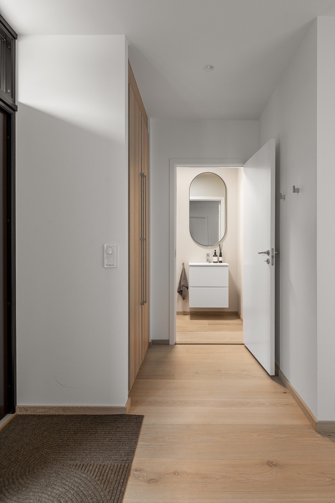 En lys og innbydende entré med parkett på gulv og malte vegger. Her er det god plass til oppbevaring av yttertøy, og entréen fremstår ryddig og praktisk. Galleribilde