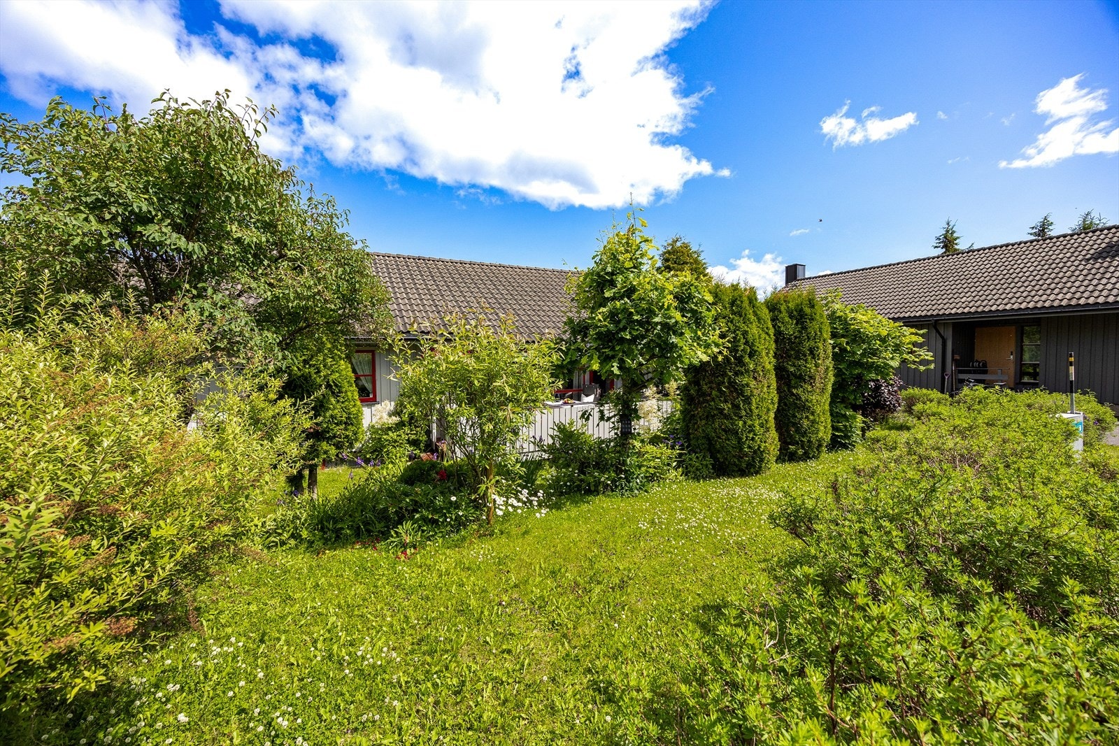 Velstelt hage med variert beplantning gir et frodig og innbydende førsteinntrykk av boligen. Galleribilde