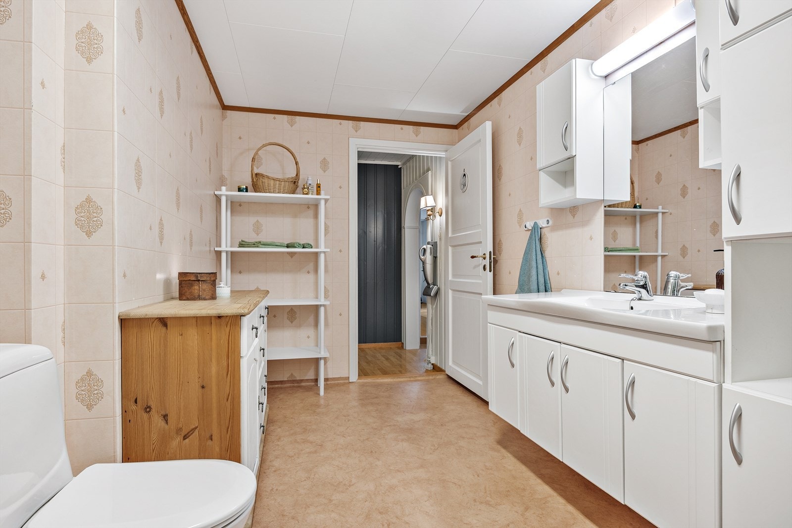 Kjellerbad med lyse baderomsplater, utslagsvask og plass til vaskemaskin og tørketrommel. Galleribilde