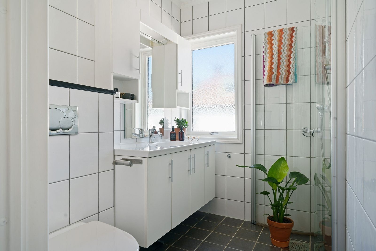 Helfliset baderom med varmekabler i gulv. Badet er innredet med vegghengt WC, servant med underskap, vegghengt skap, speil og dusjhjørne. De Galleribilde