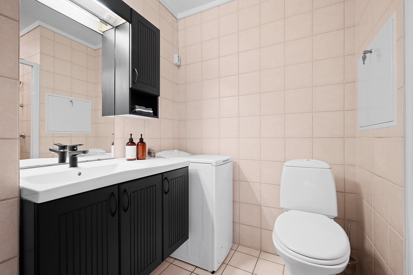 Servantskap med profilerte fronter. Overlimt servant med ettgreps armatur. Veggskap over servantskap med profilerte fronter og lysarmatur med stikk Galleribilde