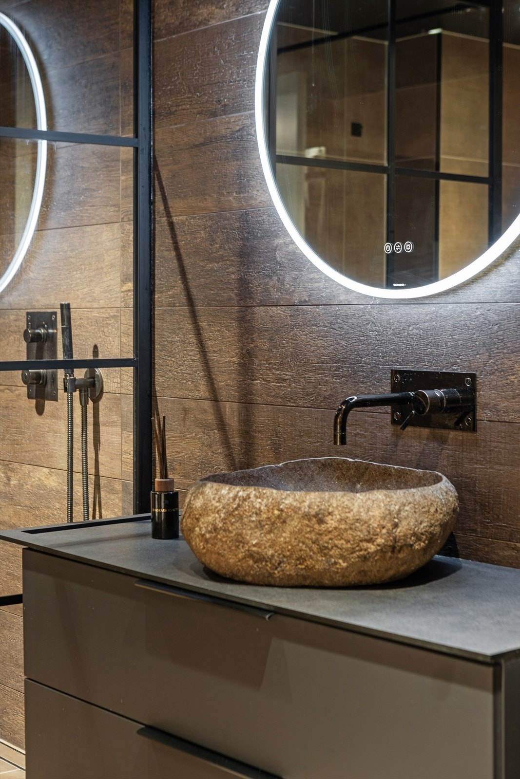 Innredningen består av vegghengt toalett med innebygget sisterne, stilren servantinnredning med steinvask og rundt speil med integrert LED-belysning. Galleribilde