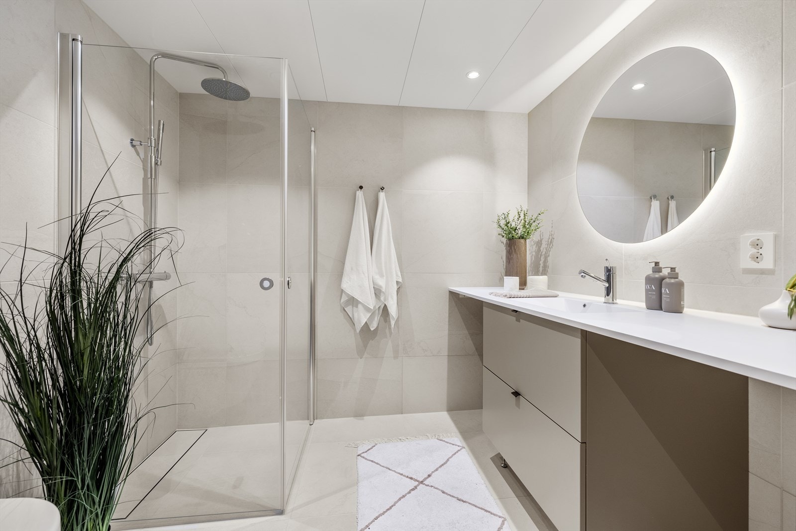 Romslig hovedbad med delikate fliser, bred servantinnredning og en stor dusjsone. Galleribilde