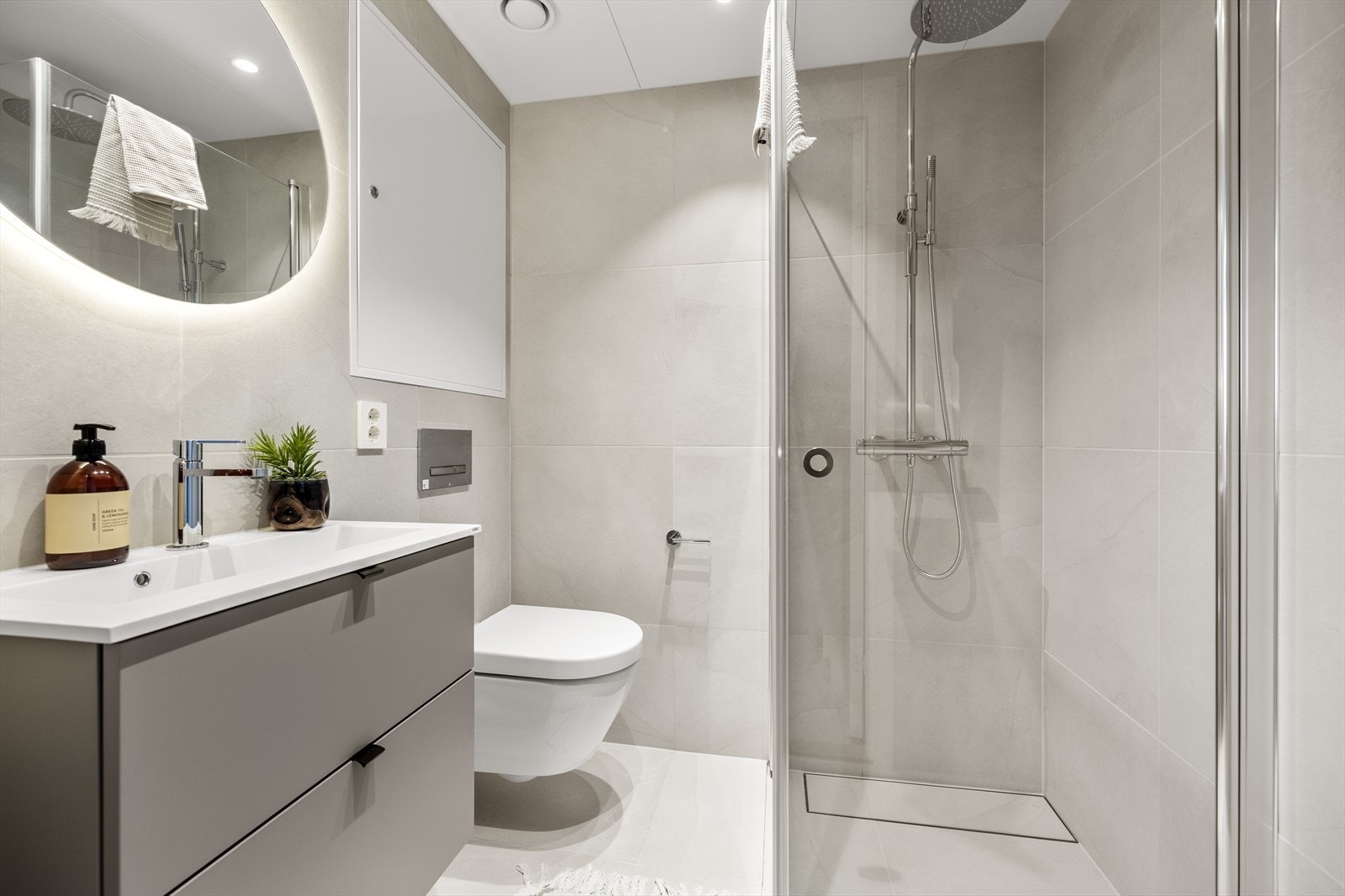 Bad med vegghengt toalett, dusjhjørne og servant med underskap. Galleribilde