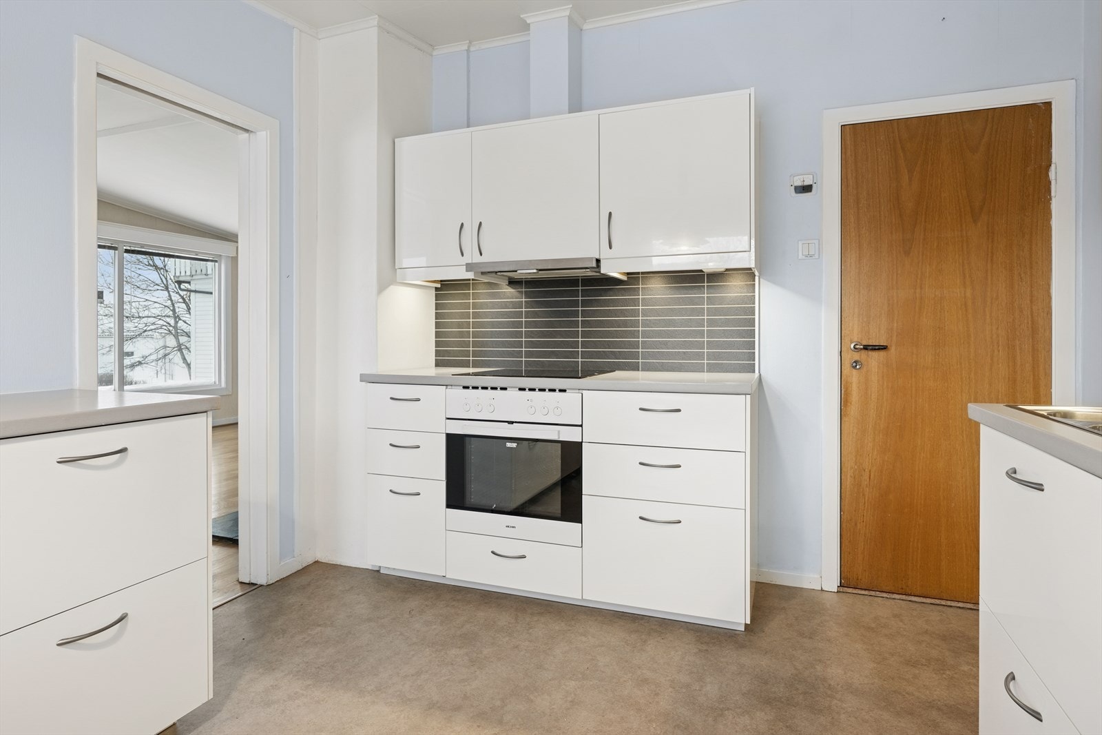 Kjøkkenet har hvite, slette fronter fra 2015 og laminat benkeplate med integrert komfyr og induksjonstopp. Galleribilde