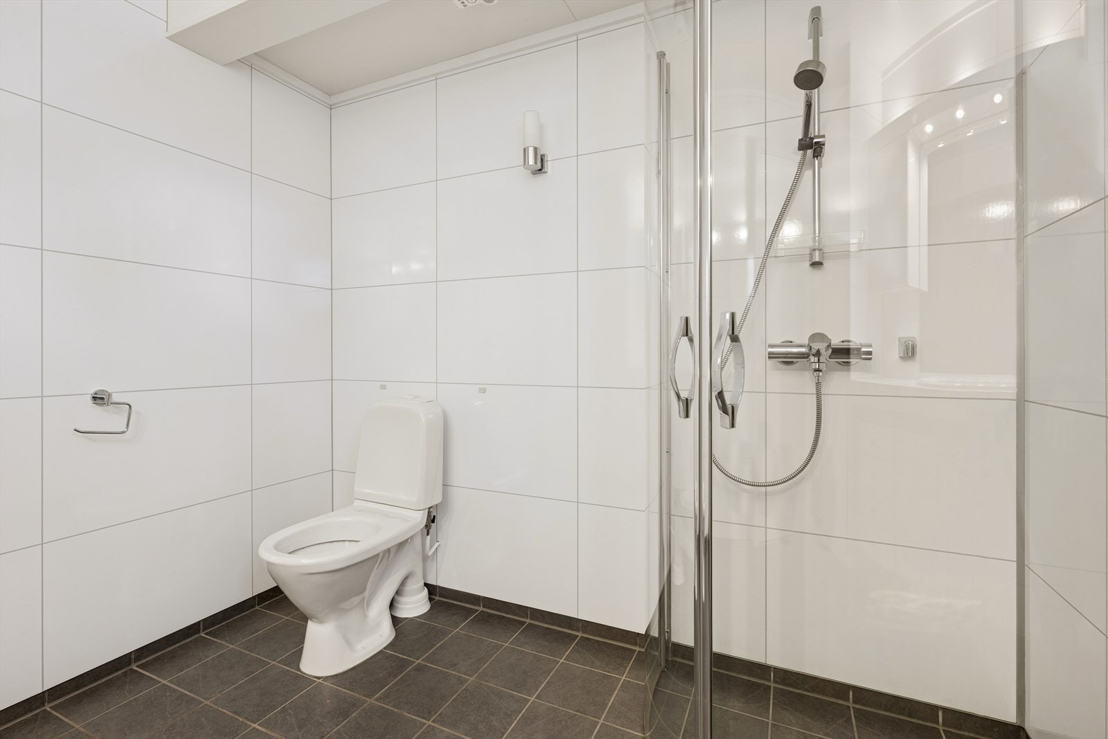 Baderommet er innredet med gulvmontert toalett, servant med skapinnredning og innfellbare dusjvegger. Galleribilde