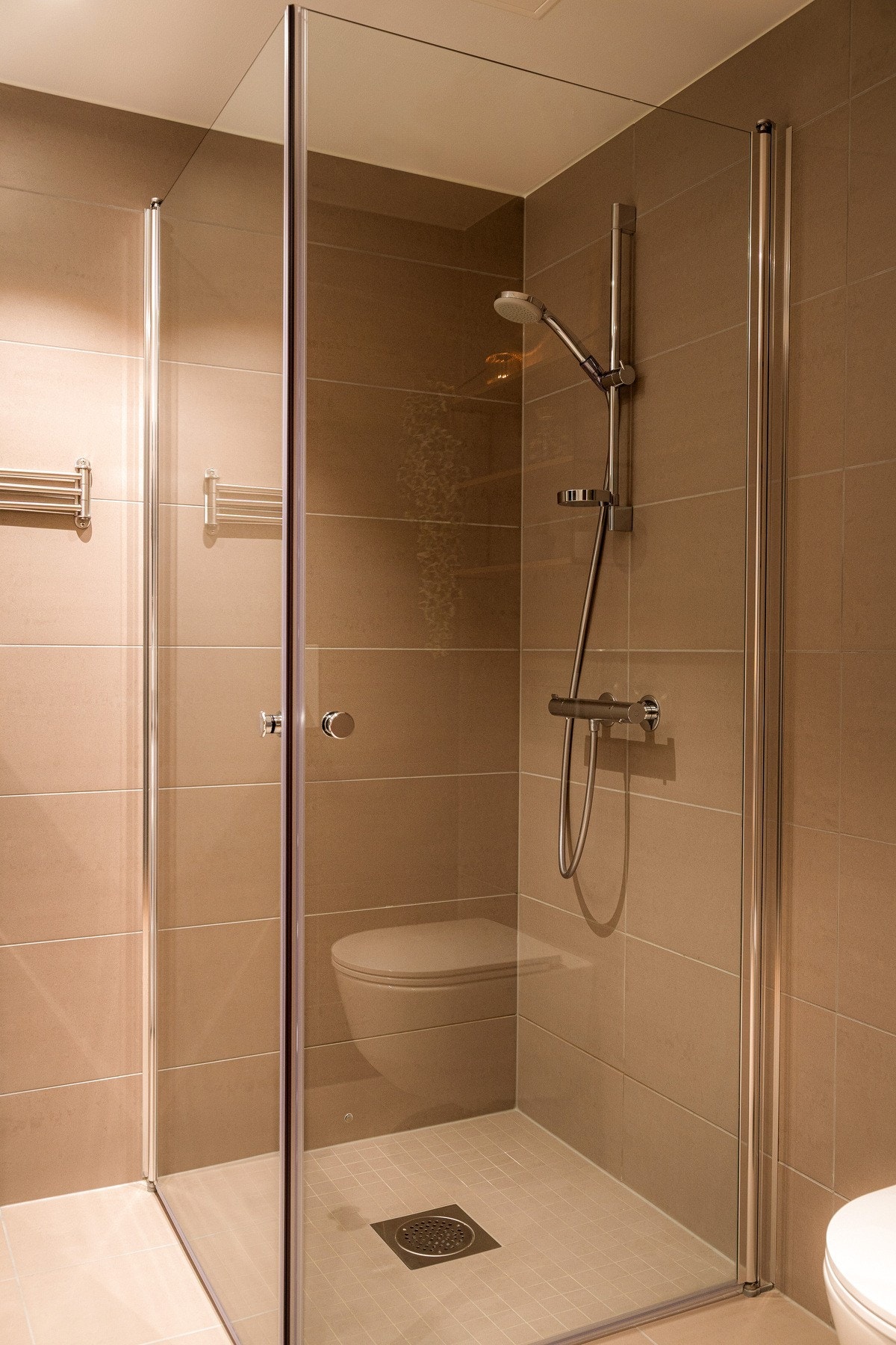 Dusjhjørne med innfellbare glassdører og dusjarmatur med hånddusj. Galleribilde