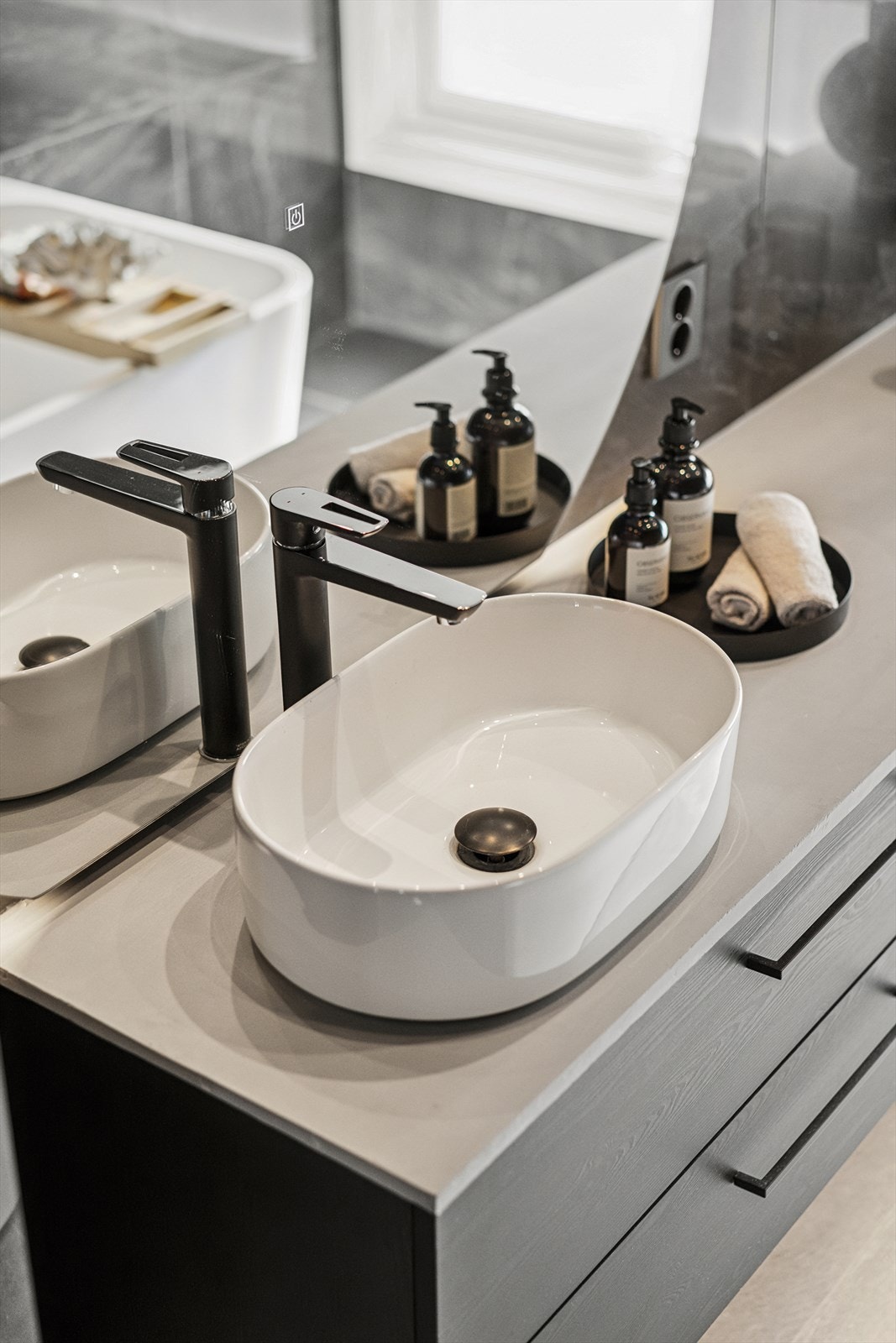 Baderomsinnredningen kombinerer funksjonalitet med estetikk, og inkluderer romslige skuffer og benkeplate med en pen vaskeservant. Galleribilde