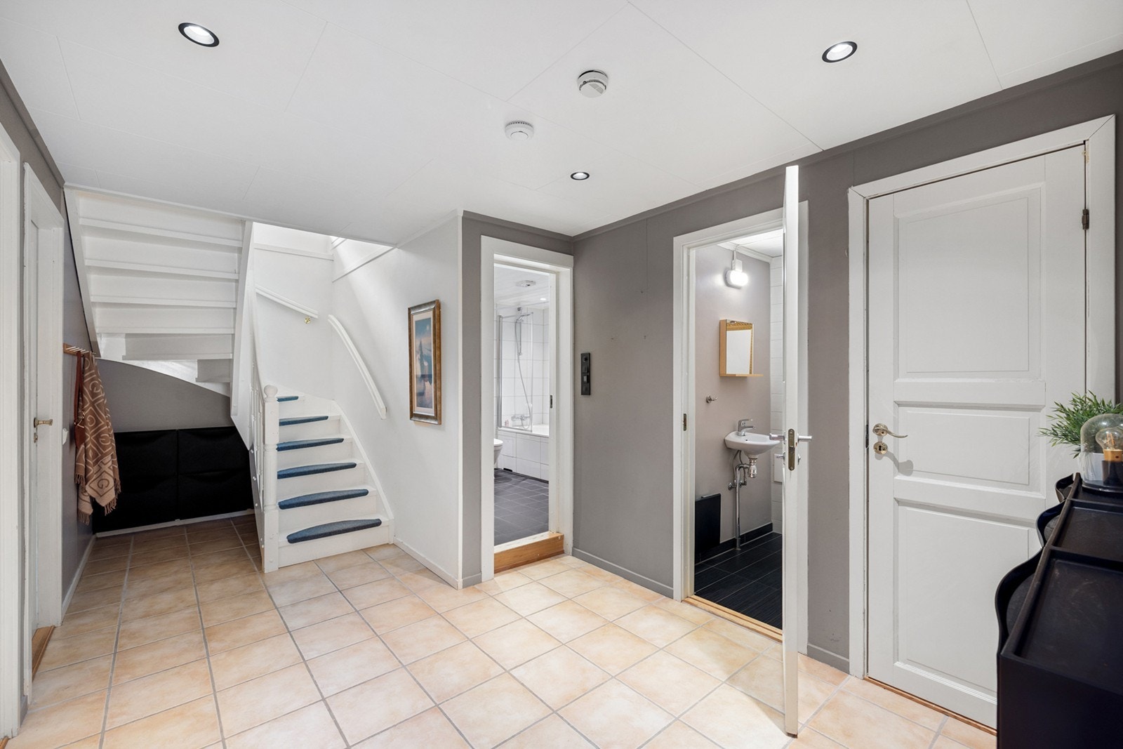 Entréen gir et ryddig og innbydende førsteinntrykk med lyse fliser på gulvet med gulvvarme, nøytrale veggfarger og god belysning fra innfelte spotter i taket. Galleribilde