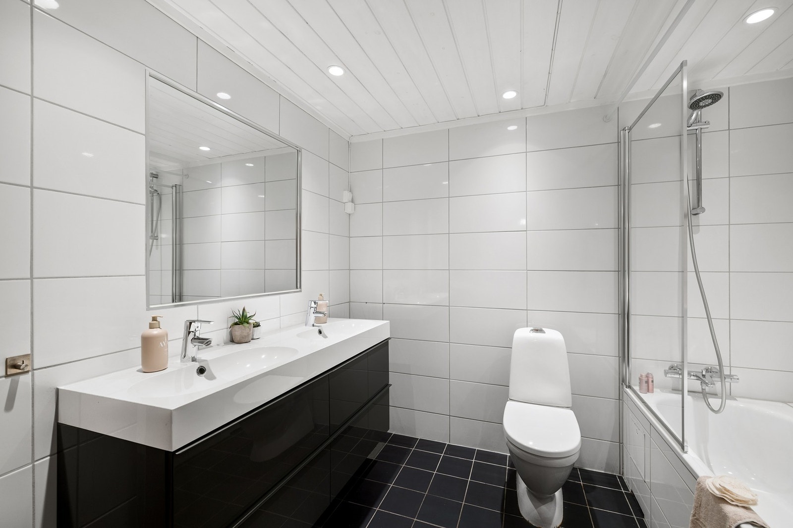 Lekkert og romslig baderom innredet med doble servanter, vegghengt innredning og stort speil med god belysning. Rommet har flislagte vegger og gulv, og gulvvarme sikrer en behagelig temperatur året rundt. Galleribilde