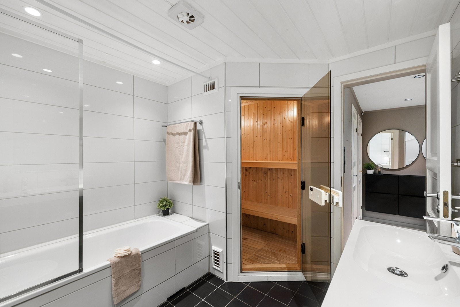 Fra badet er det direkte adkomst til en innbydende badstue i trepanel - perfekt for avslapning og velvære. Et funksjonelt og stilfullt baderom med det lille ekstra. Galleribilde