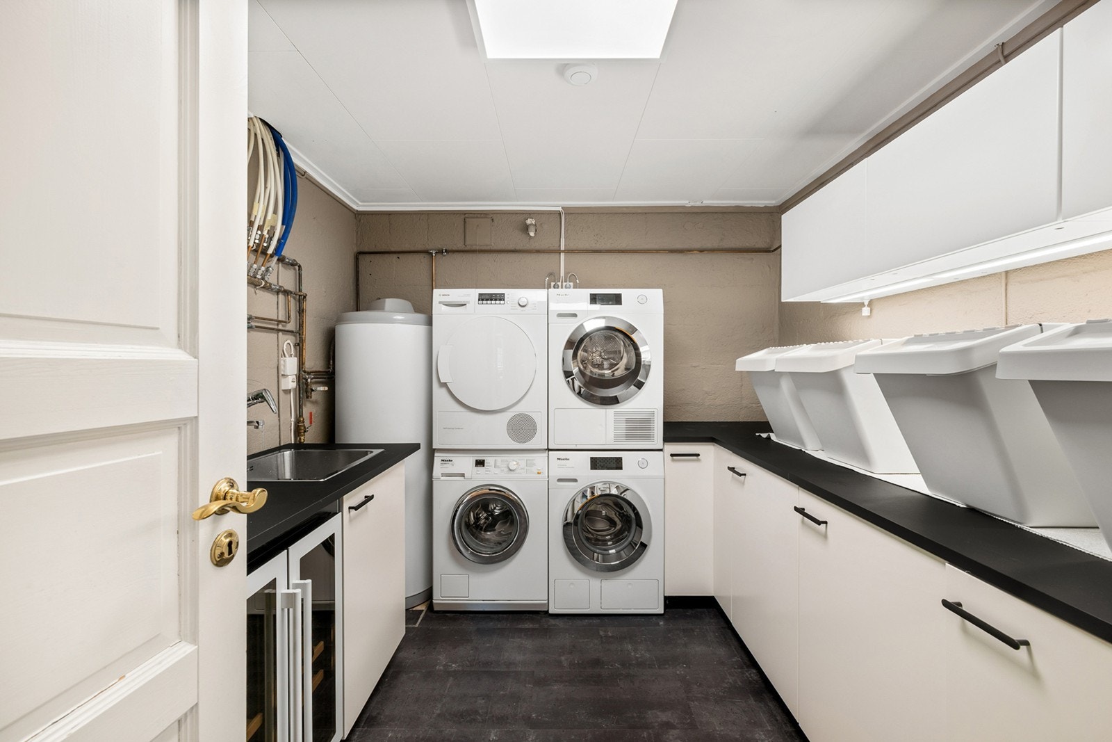 Praktisk og moderne vaskerom med rikelig benke- og skapplass, perfekt for organisering av klesvask og lagring. Galleribilde