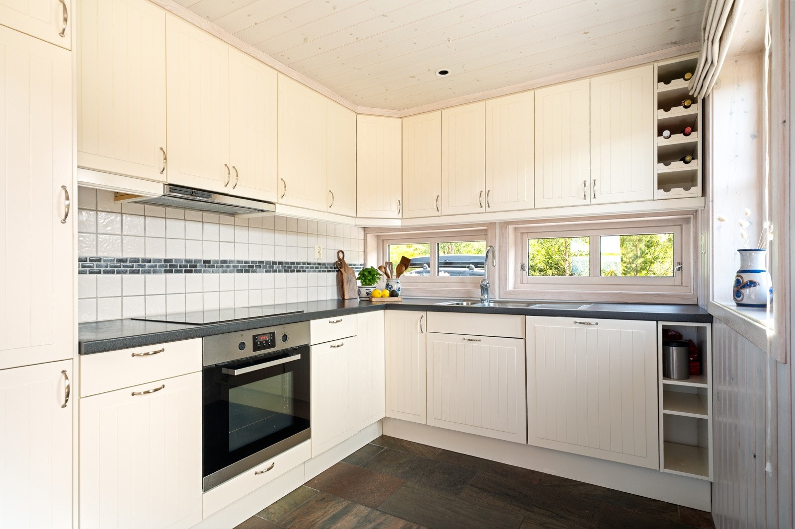 Kjøkkenet er lyst og moderne med profilerte fronter og mørke benkeplater som står i stil til resten av hytta. Galleribilde