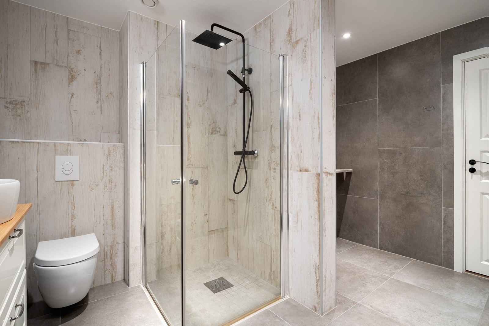 Det inneholder vegghengt toalett, dushjørne og to servanter med underskap. Galleribilde