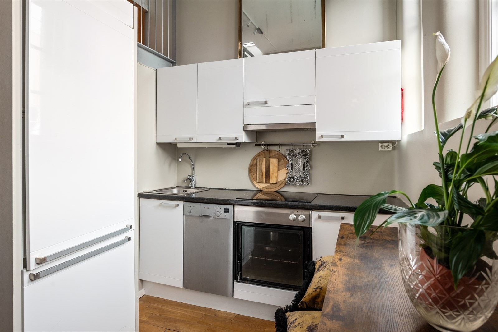 Lys kjøkkeninnredning med glatte fronter, integrert kjøleskap og overskap med plass til oppbevaring. Galleribilde