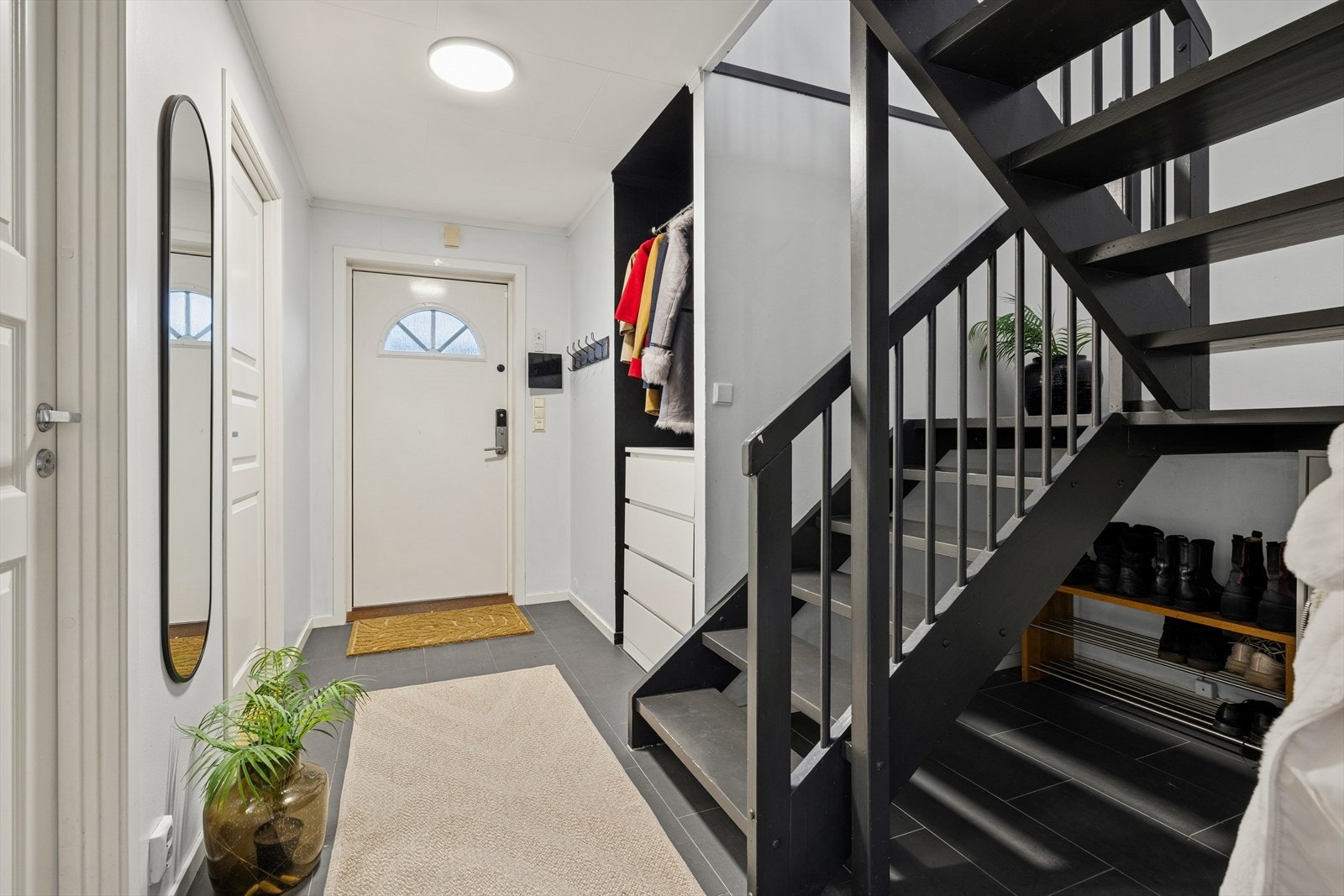 Flislagt gulv gir en praktisk og slitesterk entréløsning. Praktisk garderobeløsning. Ytterdør med kodelås. Malt innvendig tretrapp. Galleribilde