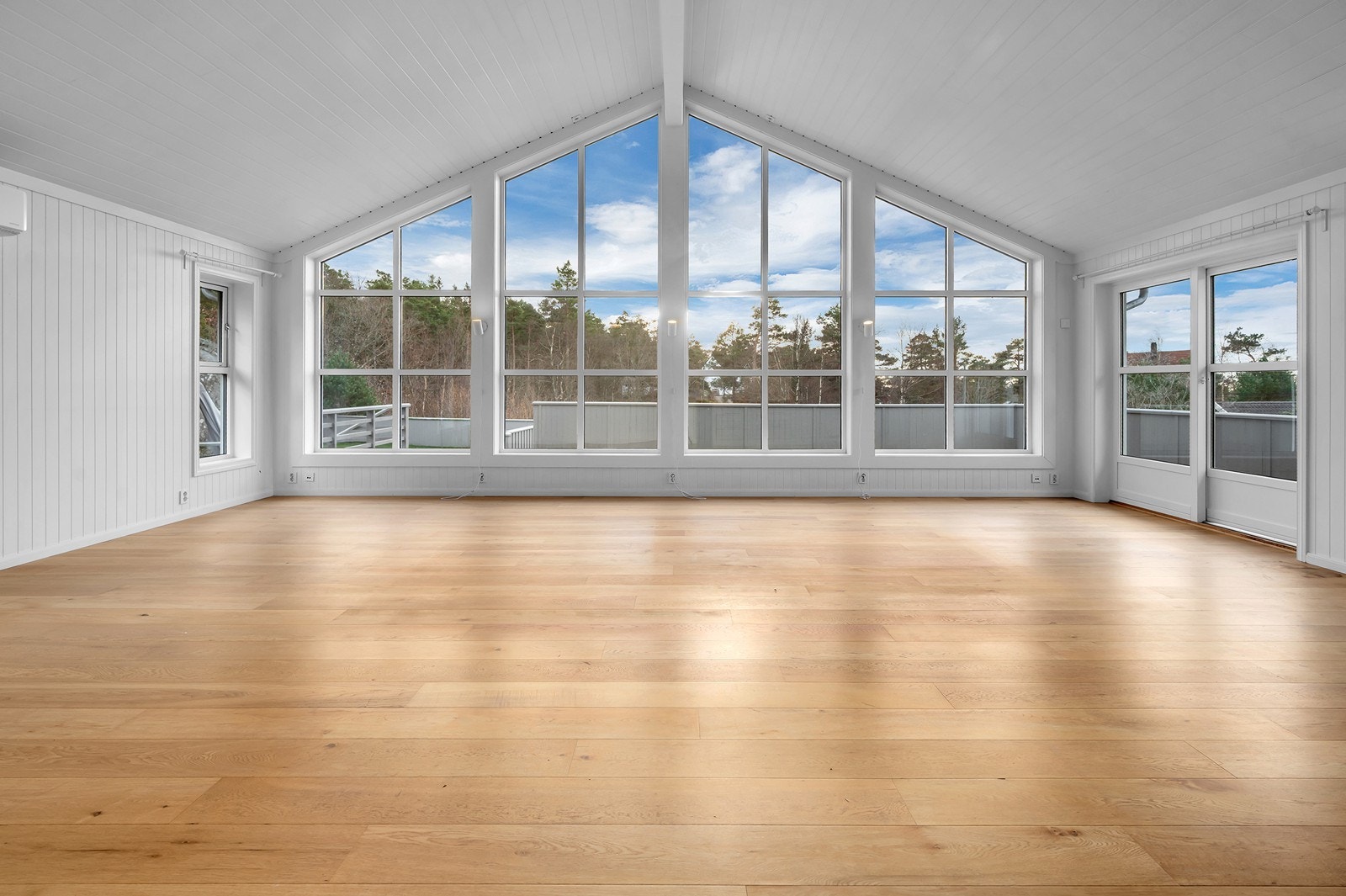 Stor stue og kjøkkendel med imponerende takhøyde og panoramavinduer som slipper inn rikelig med dagslys. Galleribilde