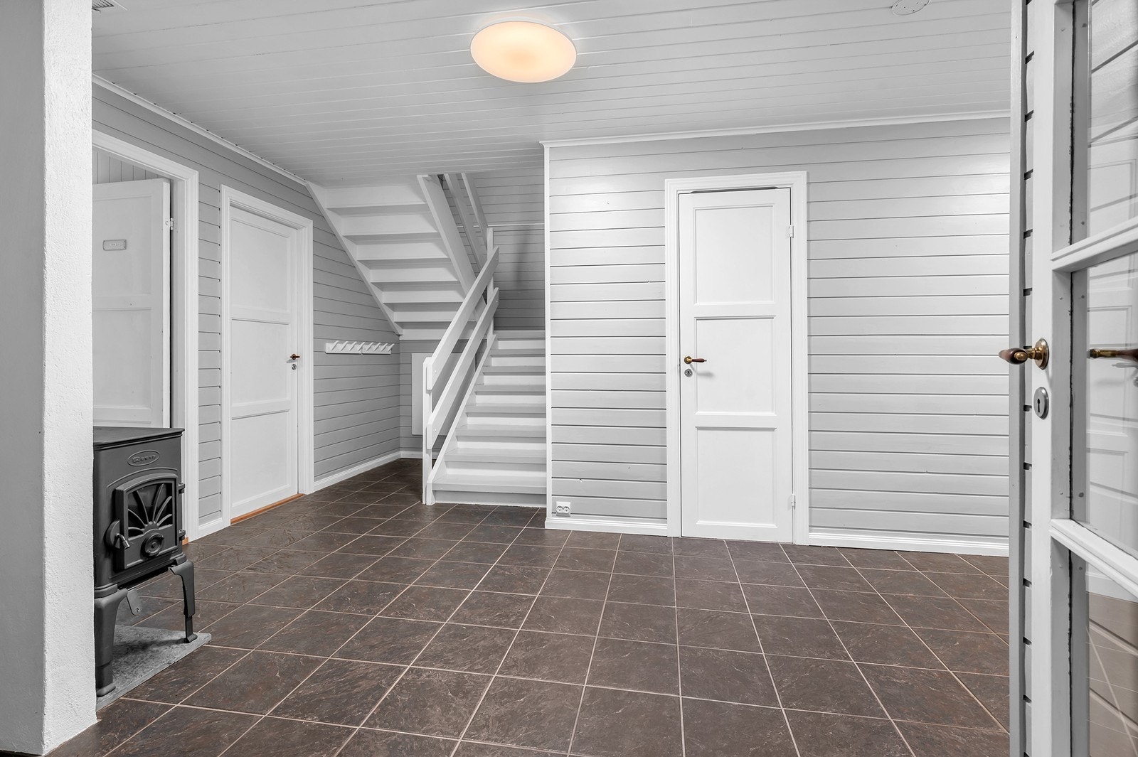 Hall i første etasje har flislagt gulv og peisovn. Galleribilde