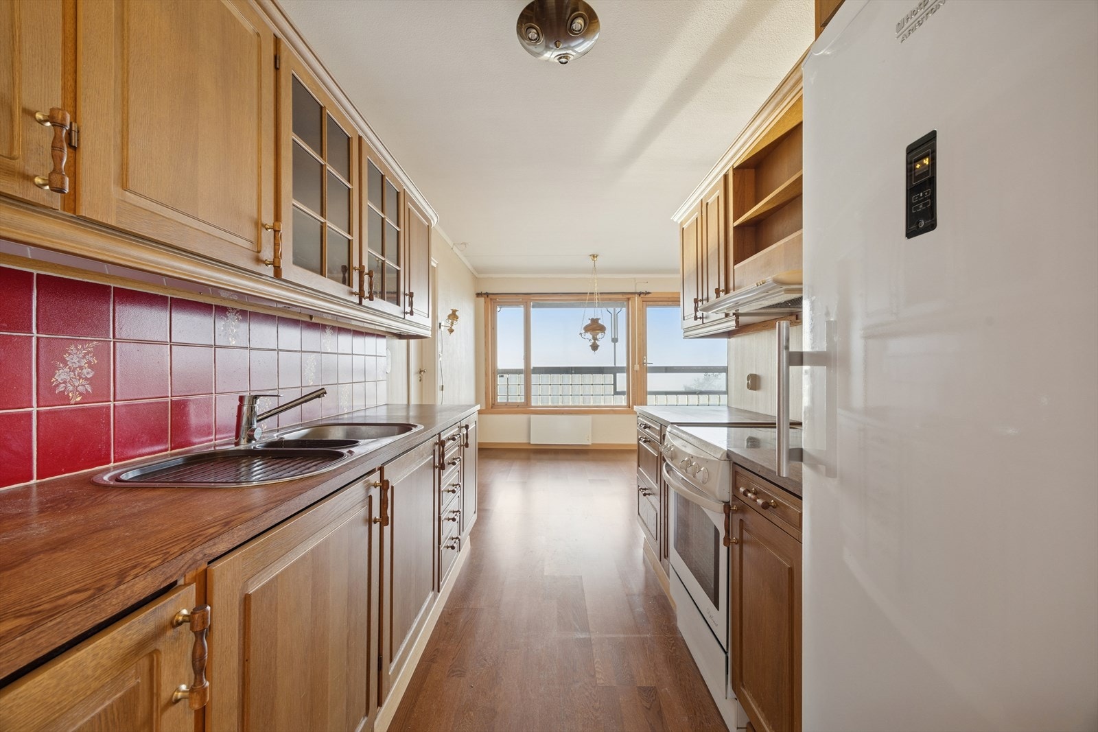 Kjøkkenet er utstyrt med oppvask- og skyllekum i rustfritt stål med tilhørende rennebeslag, flislagte og malte veggflater over kjøkkenbenkene, to vitrineskap samt belysning under overskap. Galleribilde