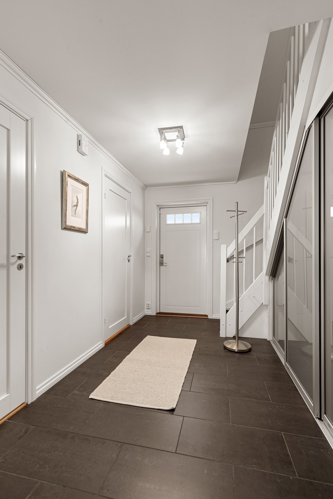 Velkommen hjem! Flislagt hall med god plass for å henge fra seg i skyvedørsløsning under trapp Galleribilde