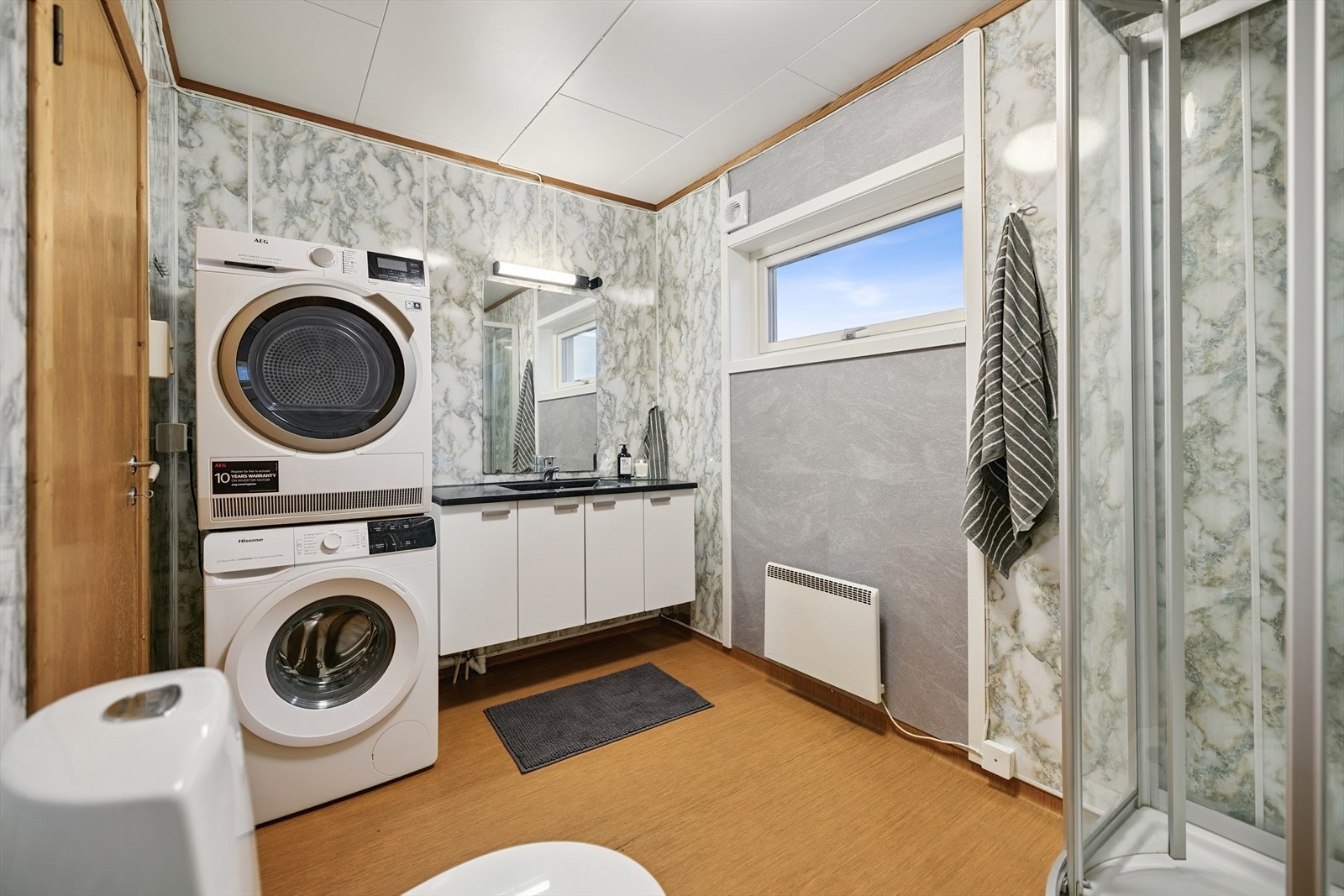 Bad med dusjkabinett, servantinnredning og opplegg for vaskemaskin. Galleribilde