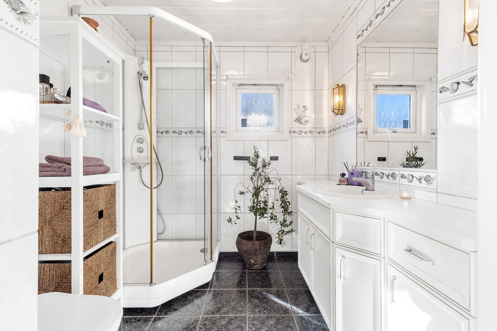 Badet har flislagte gulv og- veggflater, samt panel i himling Galleribilde