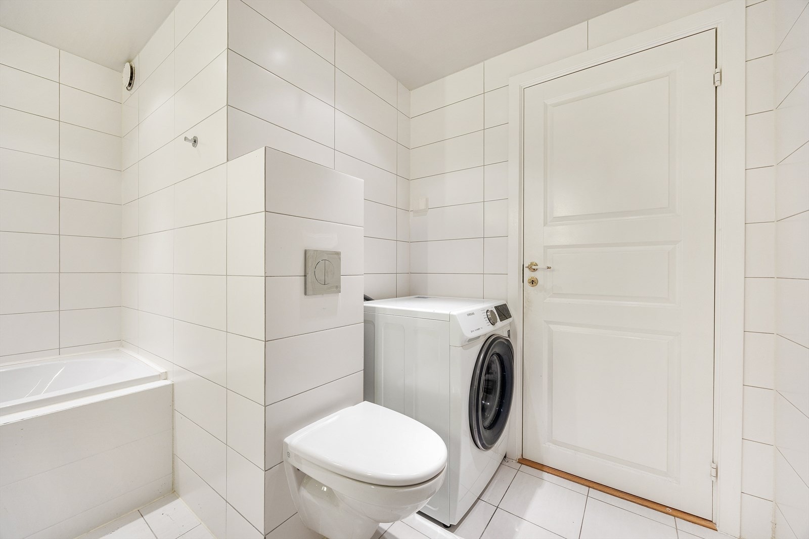 Badet har vegghengt toalett og praktisk opplegg for vaskemaskin. Galleribilde