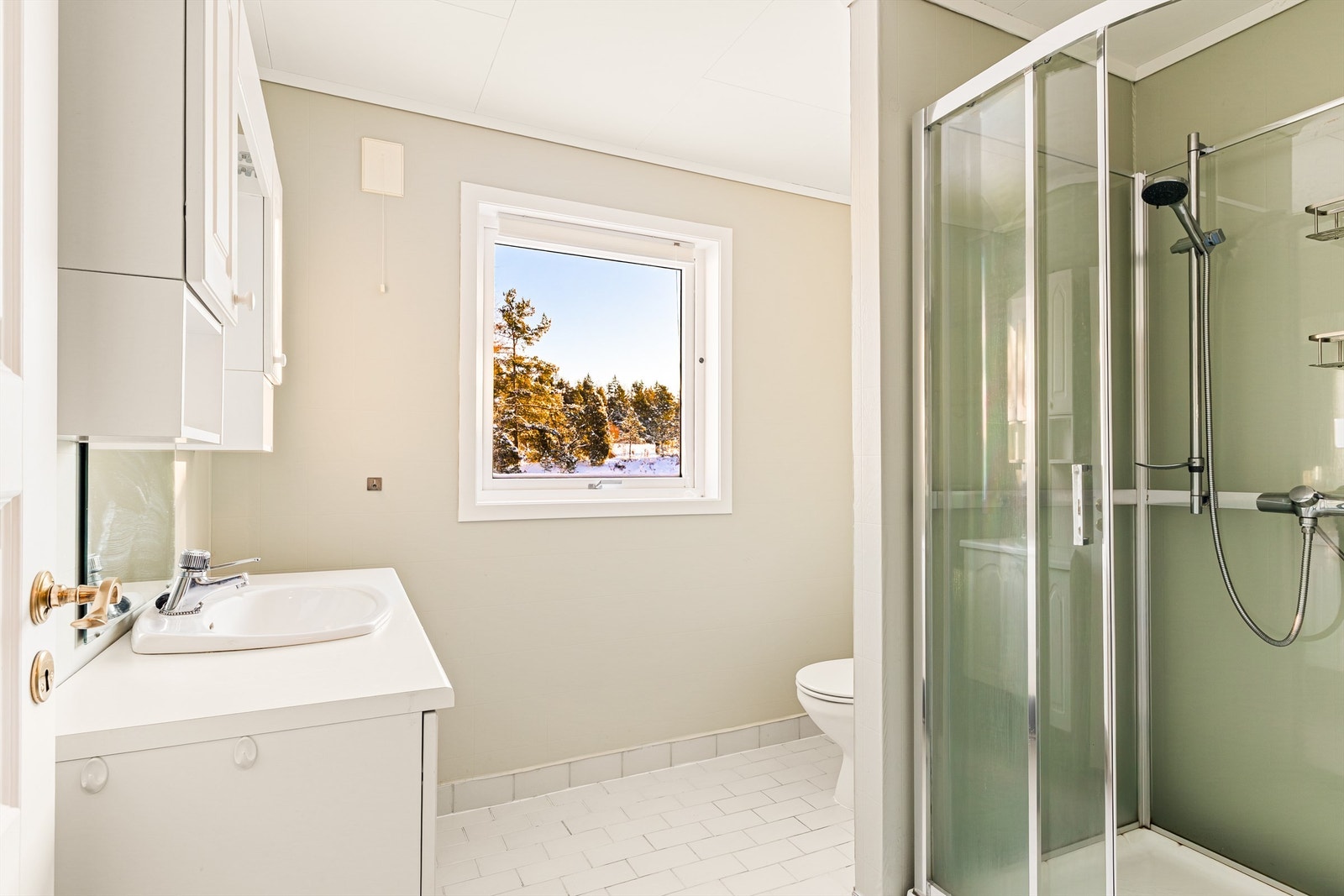 Baderom i lys utførelse med kabinett, servant i innredning og toalett Galleribilde