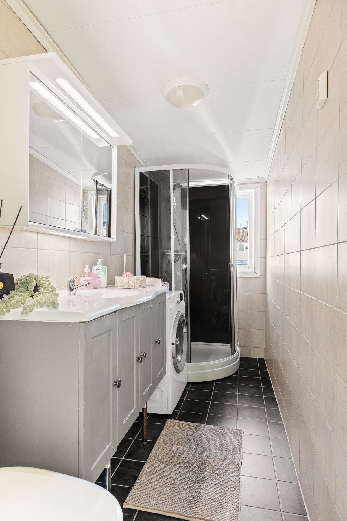 Bad med flislagte overflater og opplegg for vaskemaskin. Galleribilde