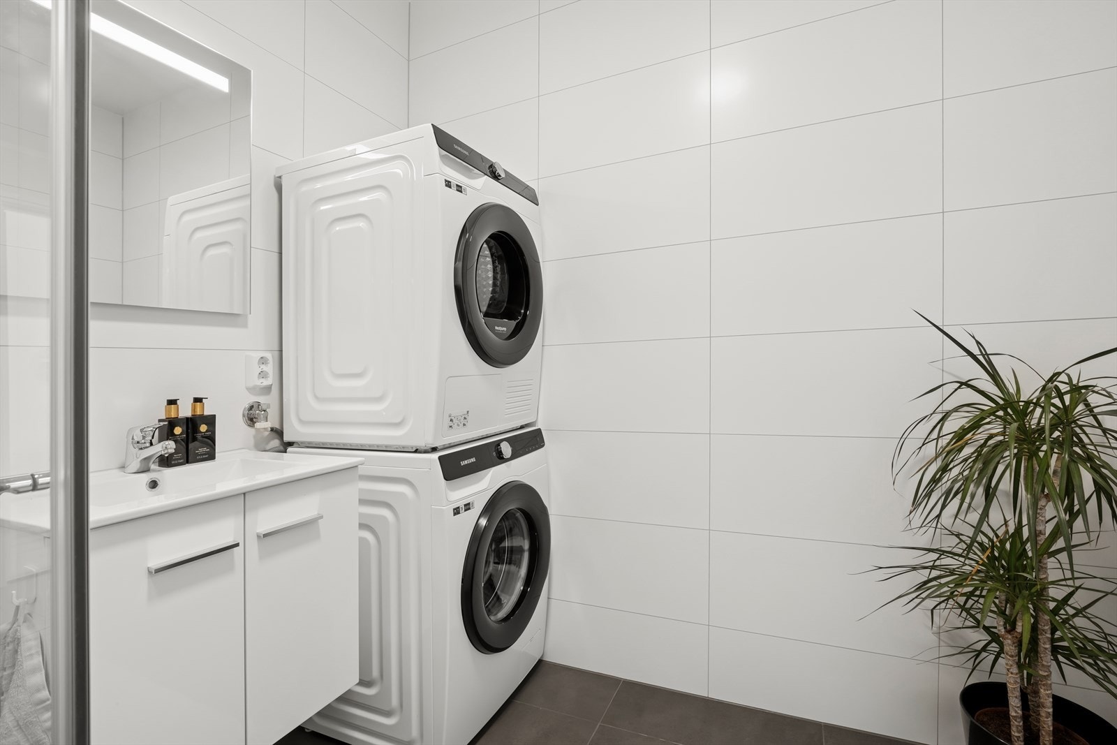 Baderommet i 1.etasje har adkomst fra gangen med opplegg for vaskemakin, dusjvegger av glass som er svingbare, servant med ettgreps kran og skap under. Galleribilde