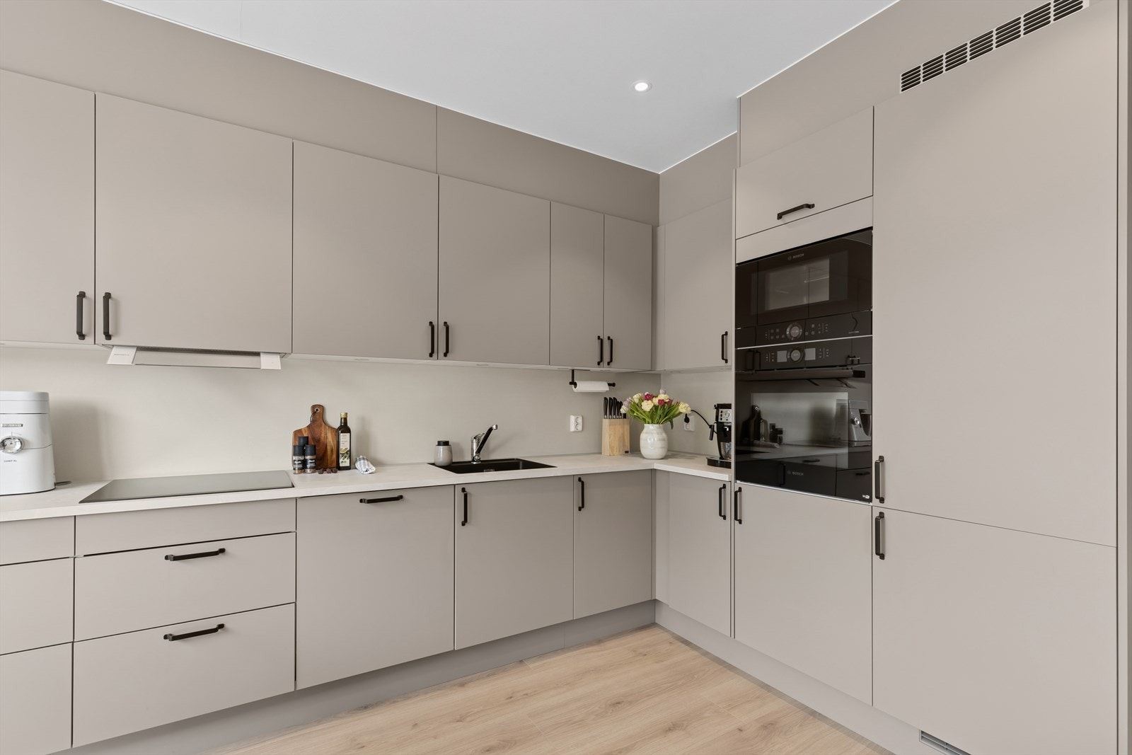 Dette moderne kjøkkenet har glatte fronter med innredning av helintegrerte og moderne hvitevarer, inkludert oppvaskmaskin og mikrobølgeovn, som gir en sømløs og ryddig helhet. Galleribilde