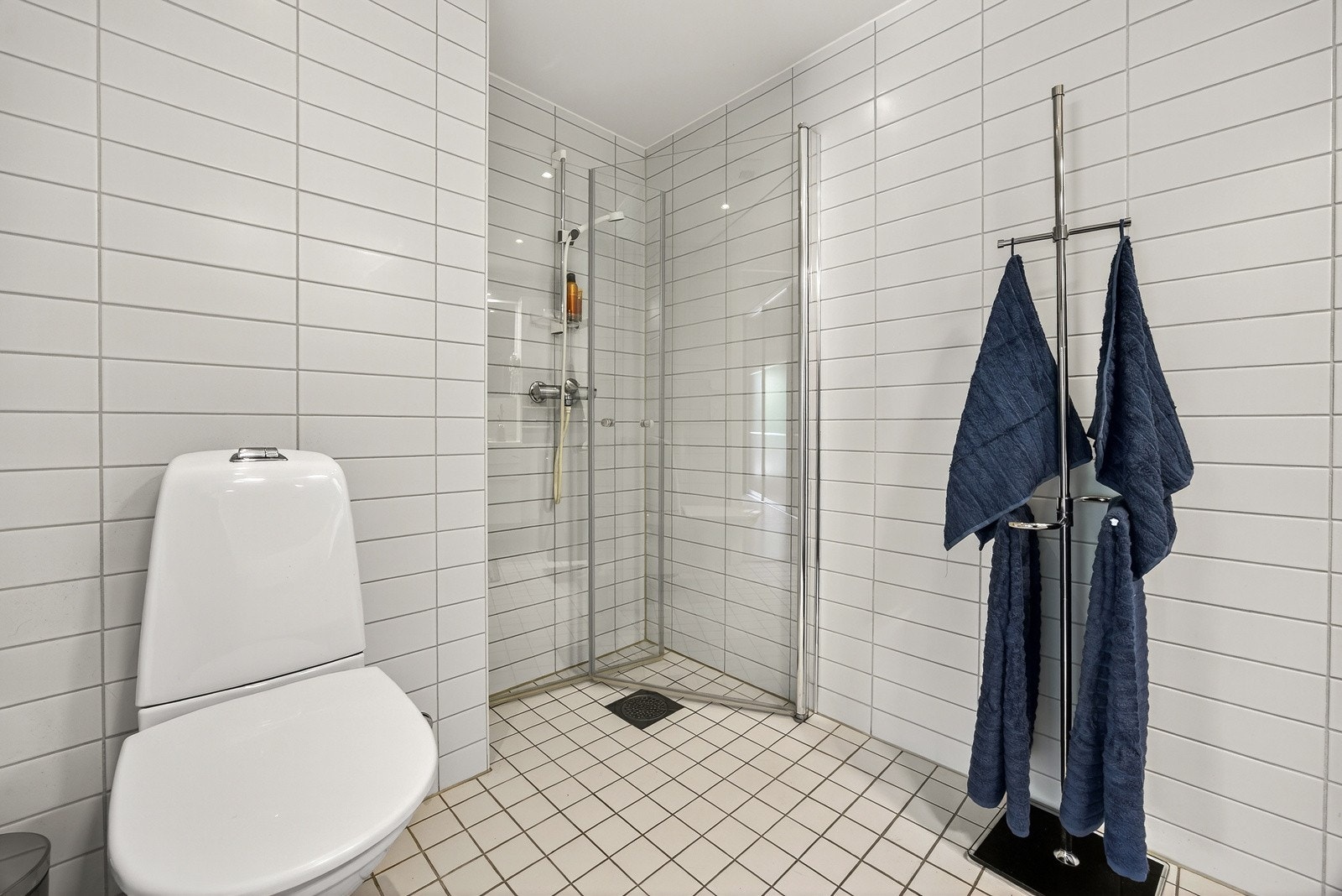 Baderomsinnredningen består av servantmøblement med glatte fronter og speilskap med belysning. Videre har badet dusjhjørne med innfellbare dører i herdet glass og veggfestet toalett. Galleribilde