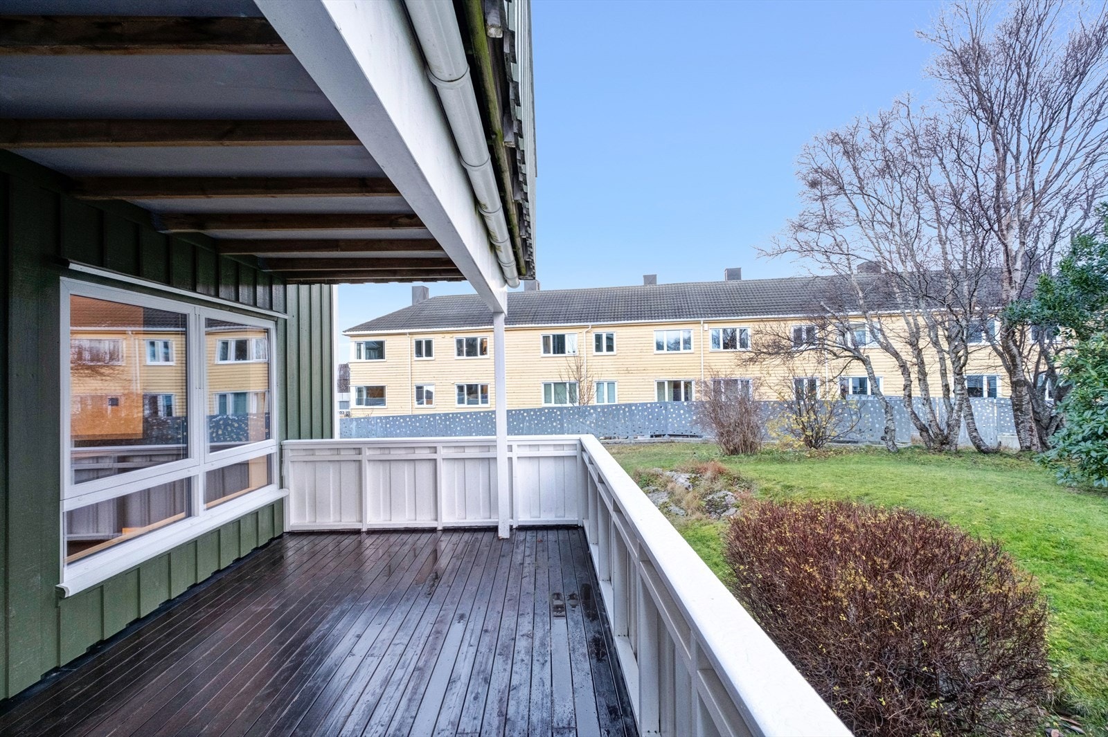 Verandaen utsyn mot felles hagemråde med plen og busker. Galleribilde