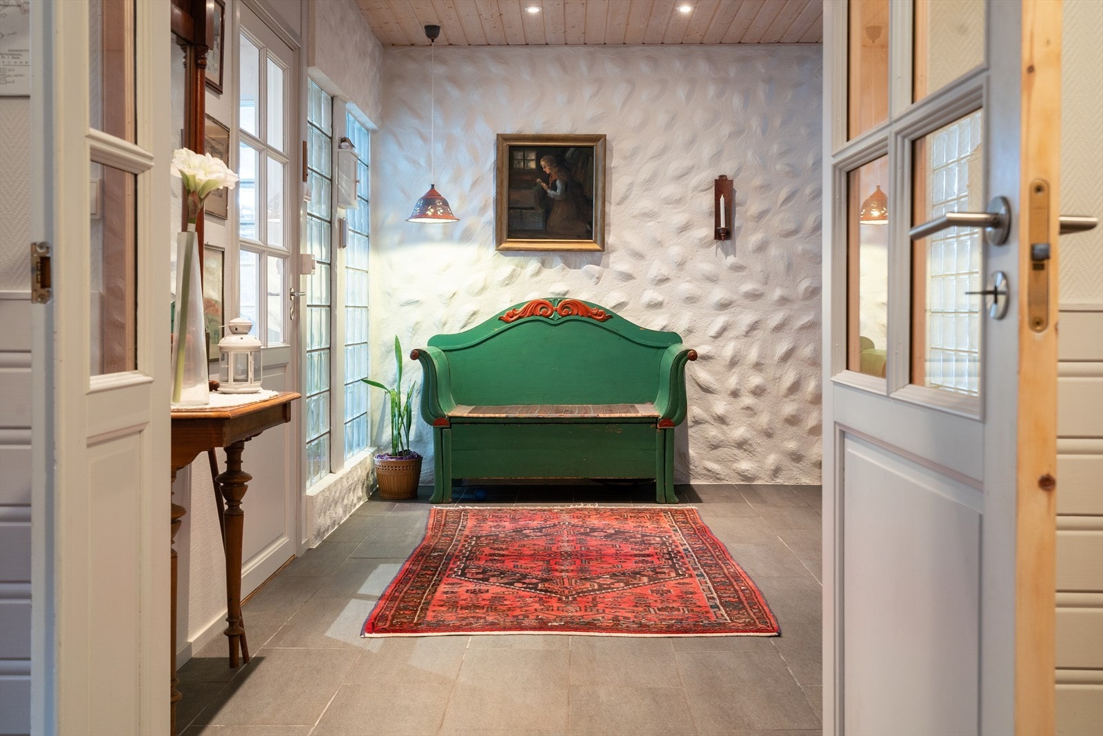 Gulvflisene fortsetter inn i en hall og et praktisk gjestetoalett. Galleribilde