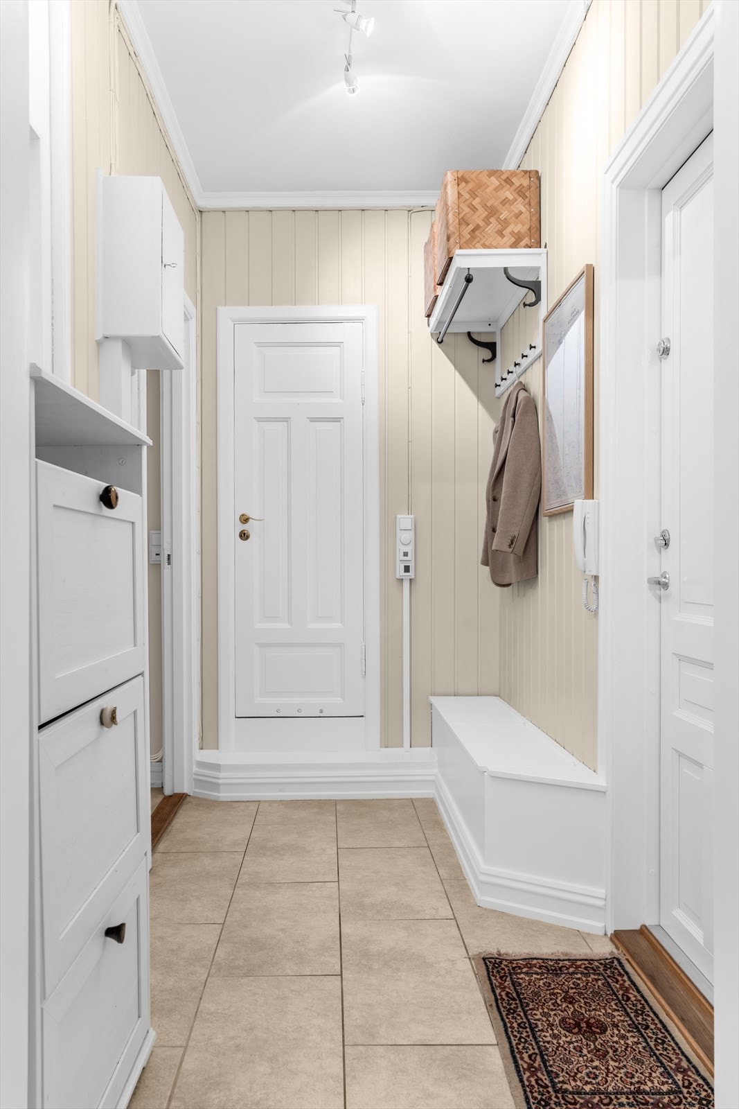 Flislagt entré med benk med oppbevaring, knaggrekke med hattehylle og plass til skoskap. Galleribilde