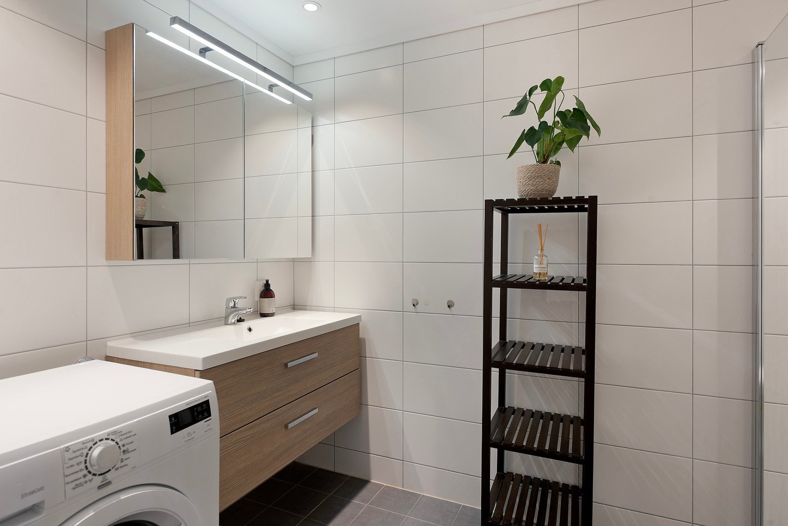 Moderne helfliset bad med god oppbevaringsplass i spesilskap og servantinnredning med skuffer Galleribilde