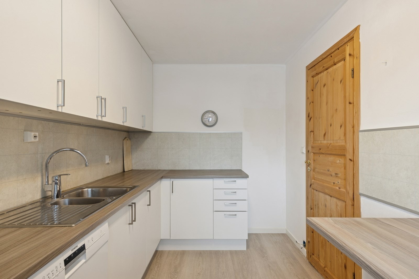 Kjøkkenet har en lys innredning fra 2007 med glatte, hvite fronter og benkeplate i laminat. Benkeplaten er delvis utstyrt med oppvaskkum, avrenningsfelt og kjøkkenarmatur. Galleribilde