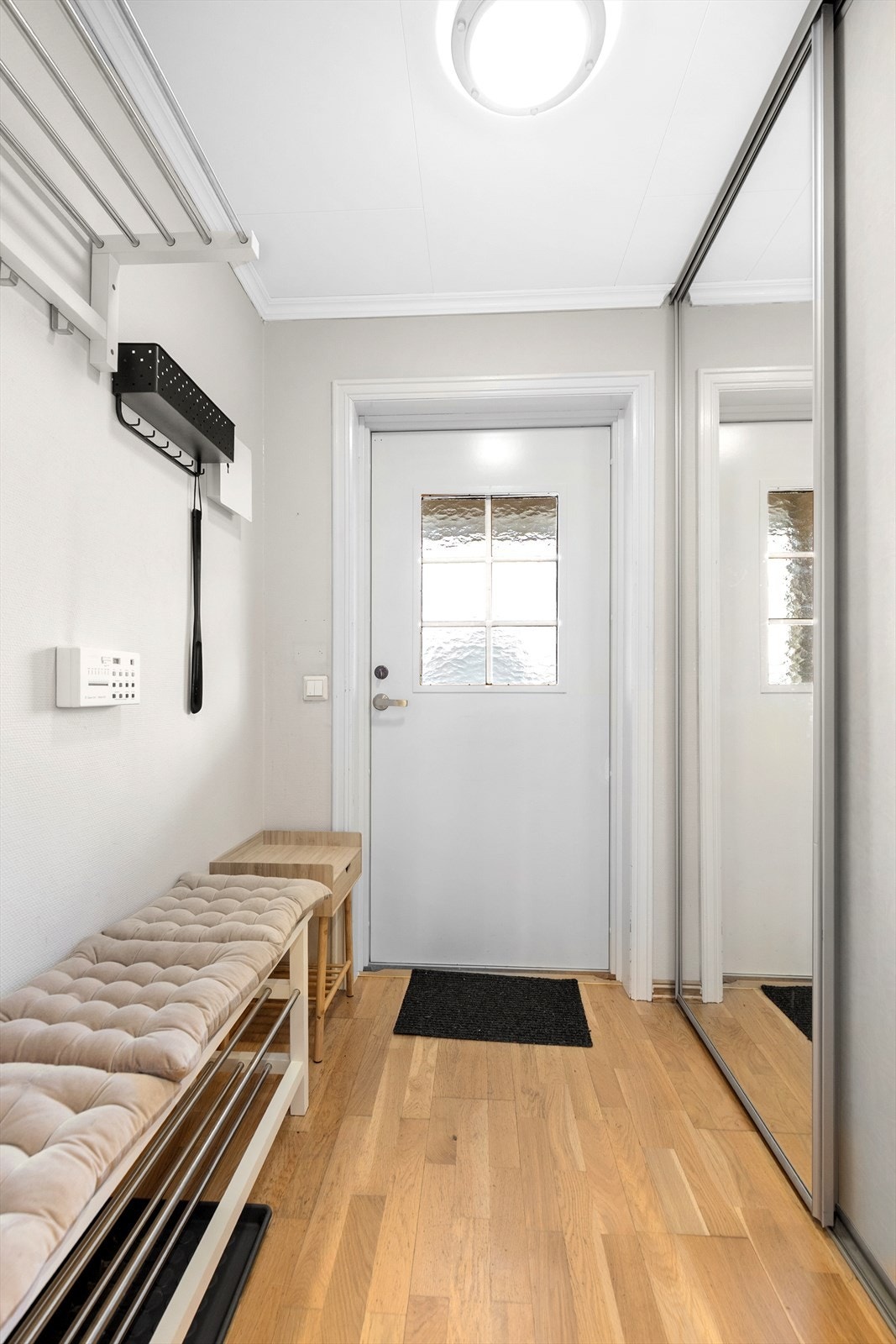 Med adkomst fra den hyggelige felles svalgangen kommer man inn i boligens romslige gangarealer. Her er det i yttergangen en god skyvedørsgarderobe med speildører for oppbevaring av sko- og ytterklær. Galleribilde
