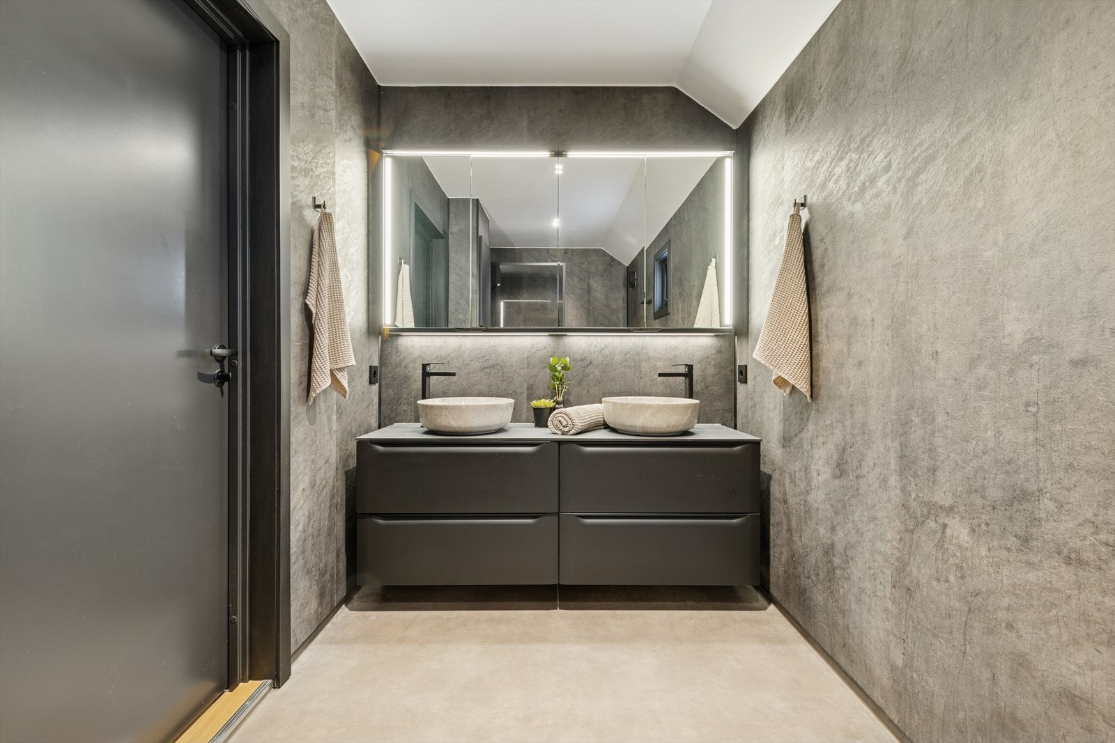 Badet er ellers utstyrt med dusjhjørne, vegghengt toalett og baderomsinnredning med dobbel servant. Her er sorte detaljer gjennomgående, noe som gir et lunt og moderne uttrykk. Galleribilde