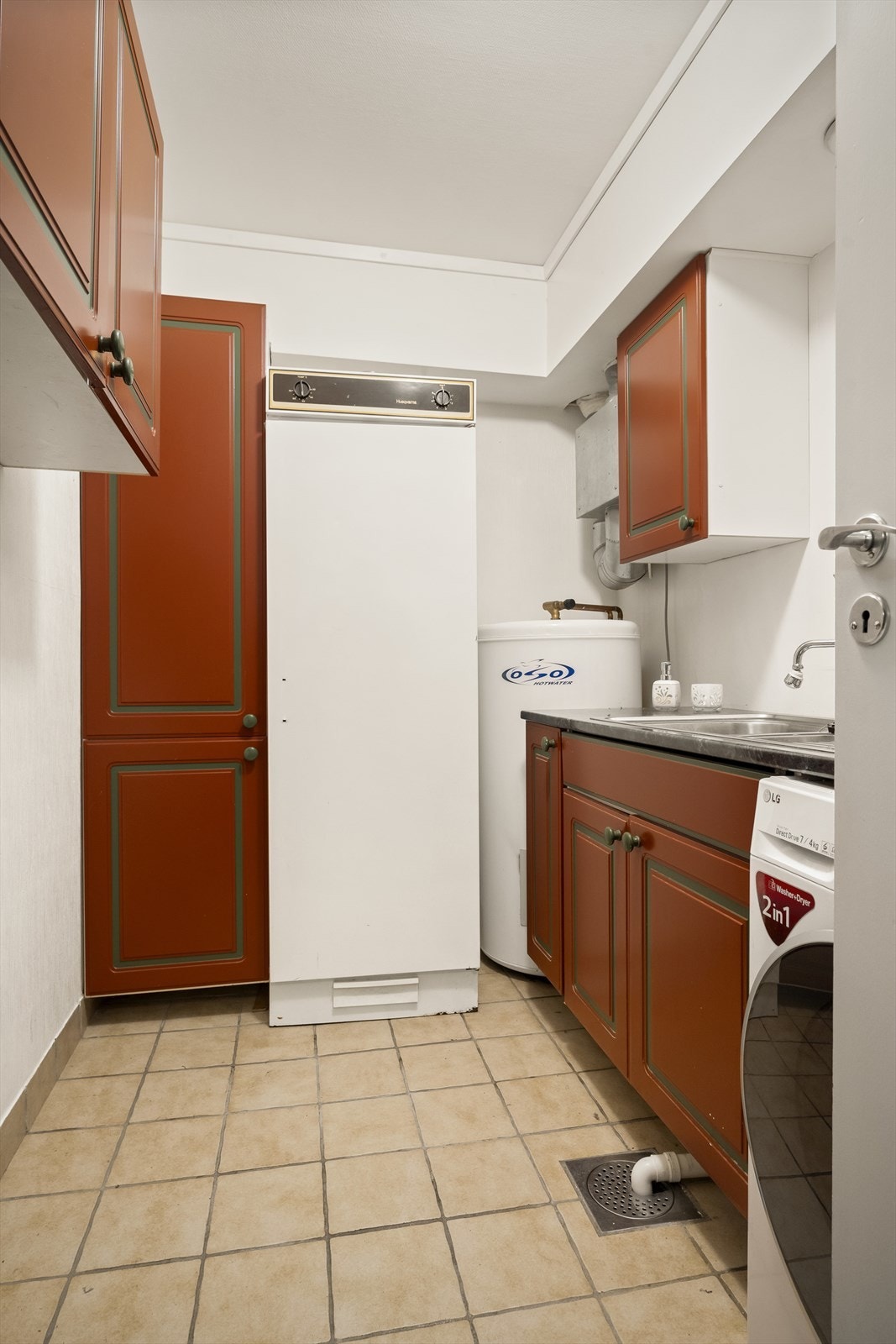 Vaskerom i u.etasje med flislagte overflater på gulv og malt våtromstapet på vegger. Rommet er innredet med vaskeromsinnredning med profilerte mørke fronter, benkeplate og høyskap. Videre er det nedfelt vaskekar med veggarmatur og opplegg for vaskemaskin. Galleribilde